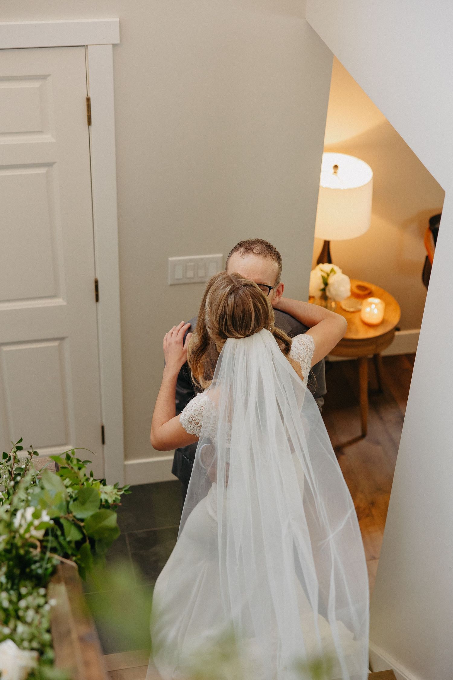 A tender wedding moment captured as a couple shares a heartfelt embrace in a warmly lit interior.