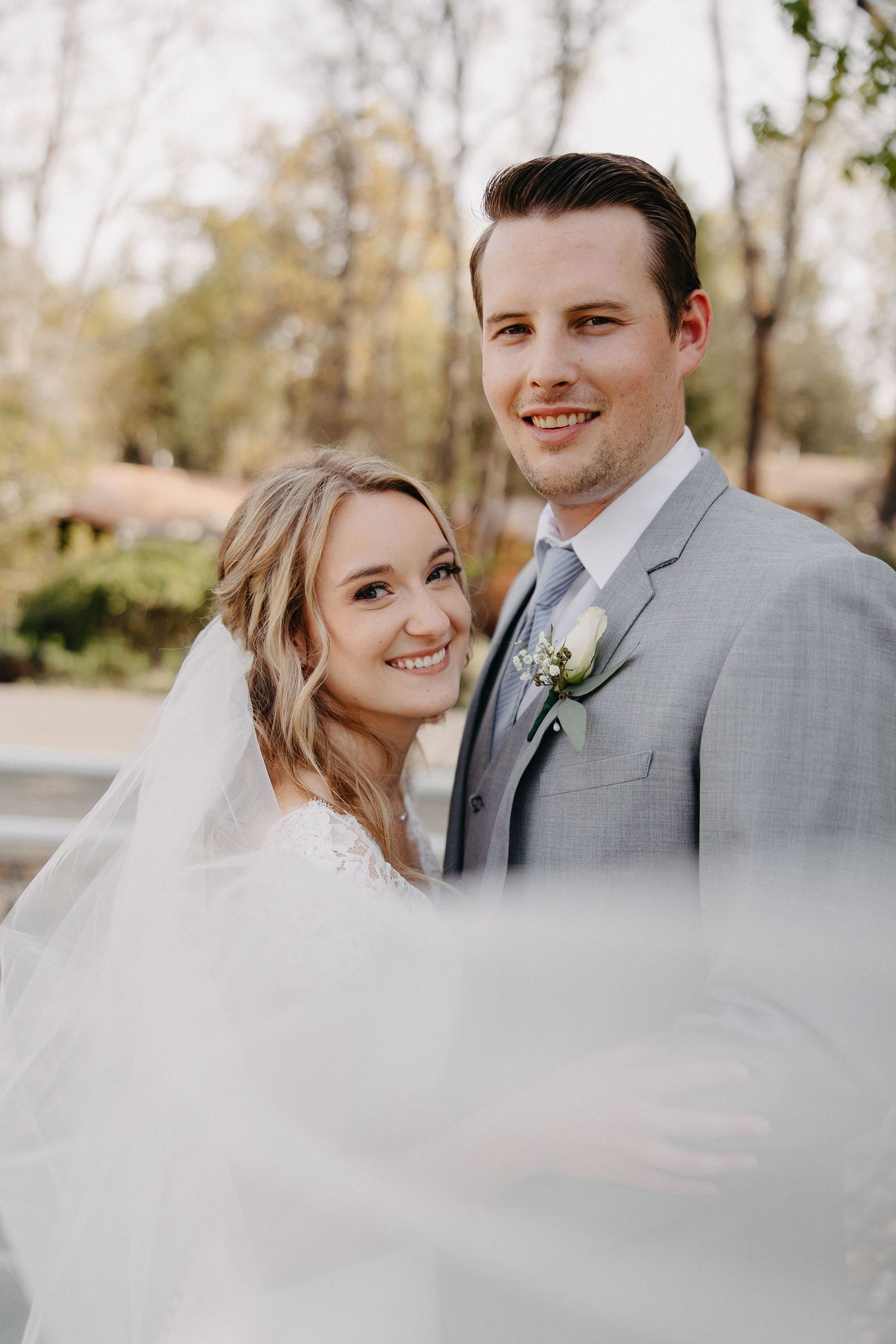 Beautiful outdoor wedding portrait with soft natural lighting and flowing veil detail.