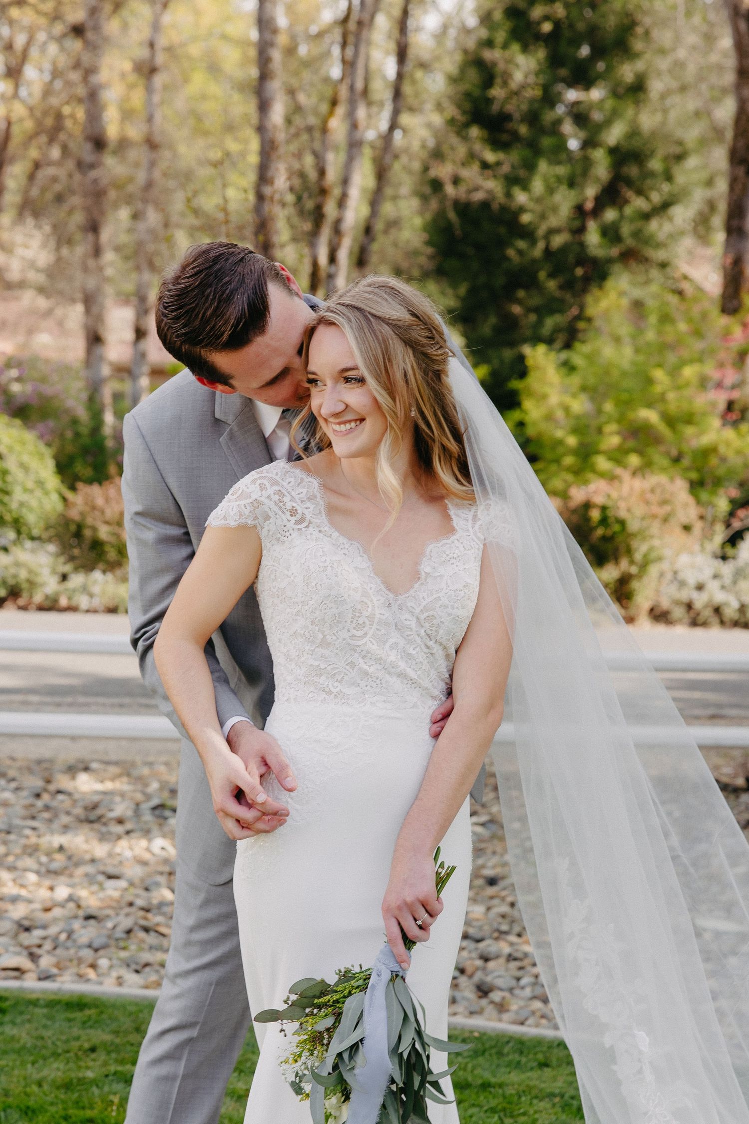 A romantic outdoor wedding portrait showing the couple sharing a joyful moment.