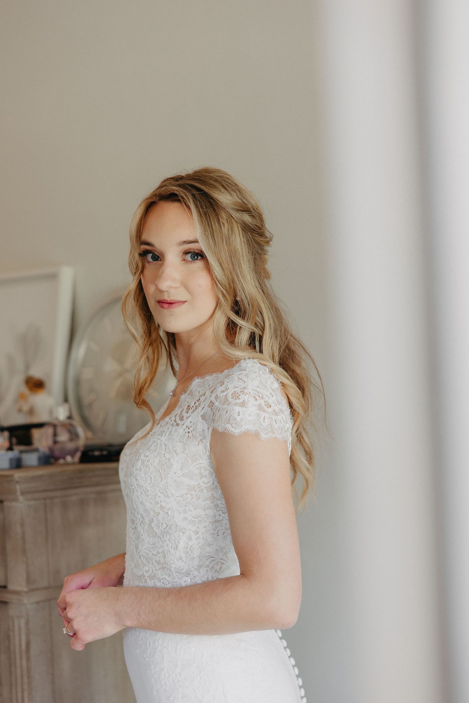 A serene portrait in a cap-sleeve lace wedding gown by a vintage dresser.