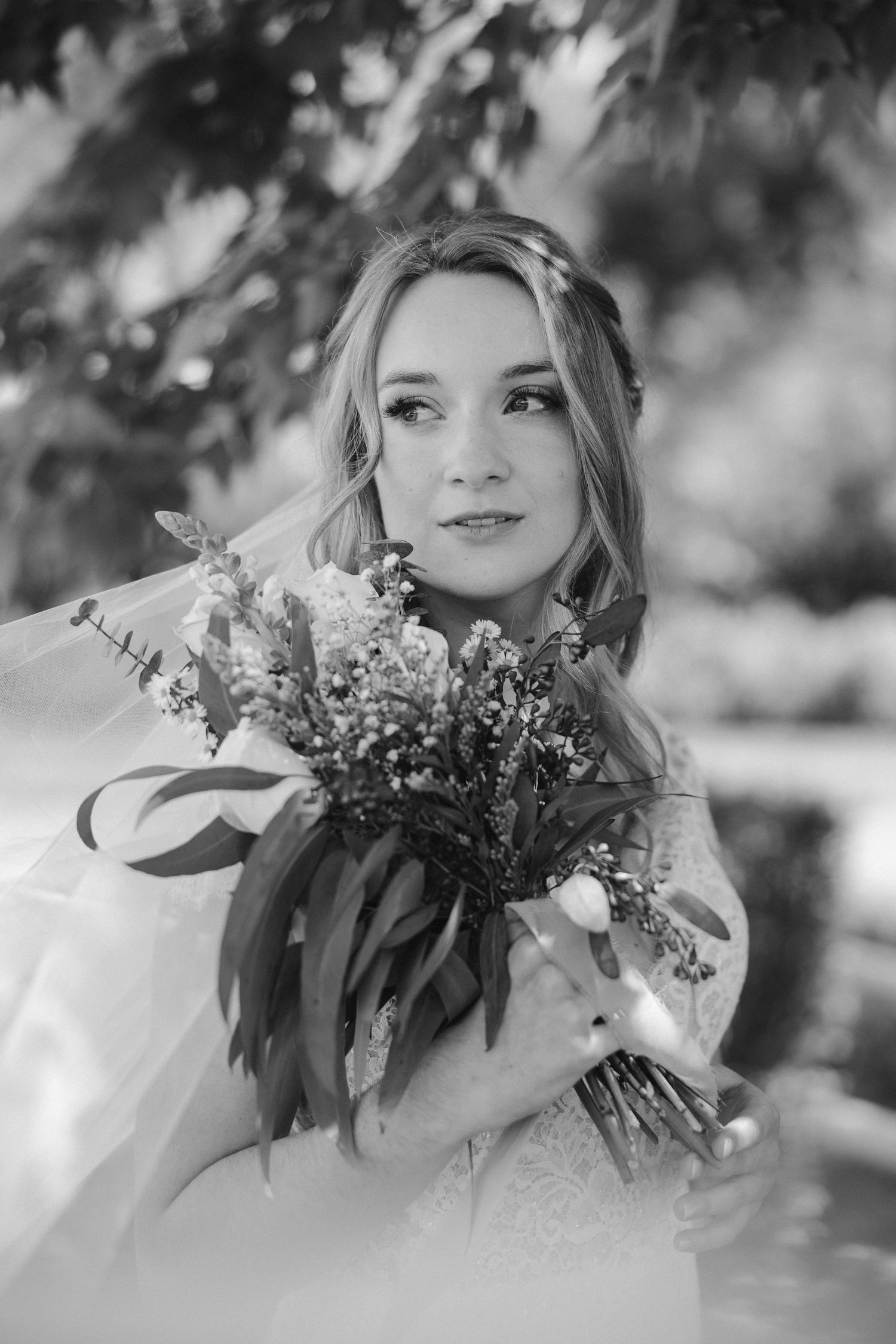 Black and white portrait of a bride holding a delicate bouquet of wildflowers.