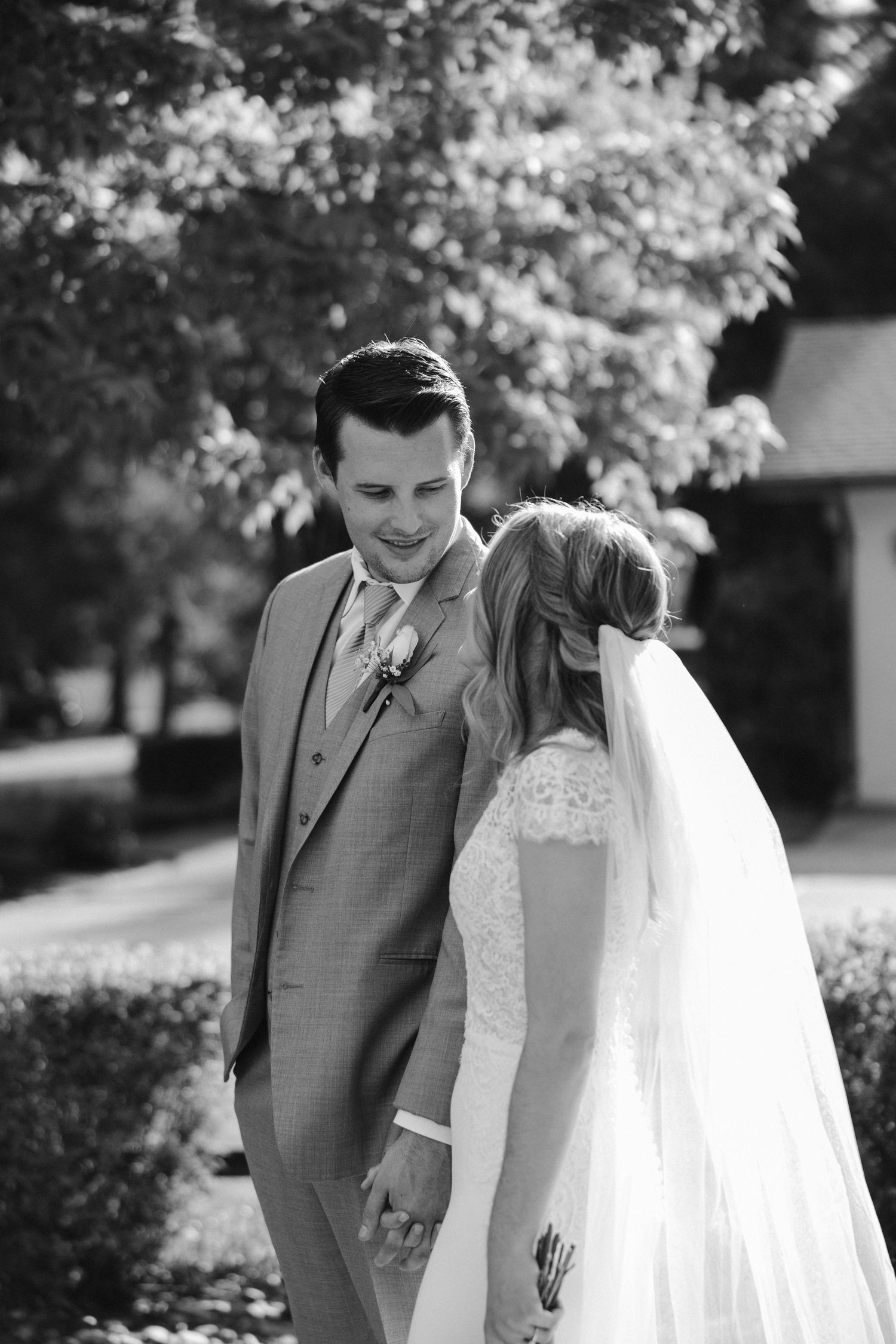 A black and white candid moment between newlyweds sharing a loving glance outdoors.