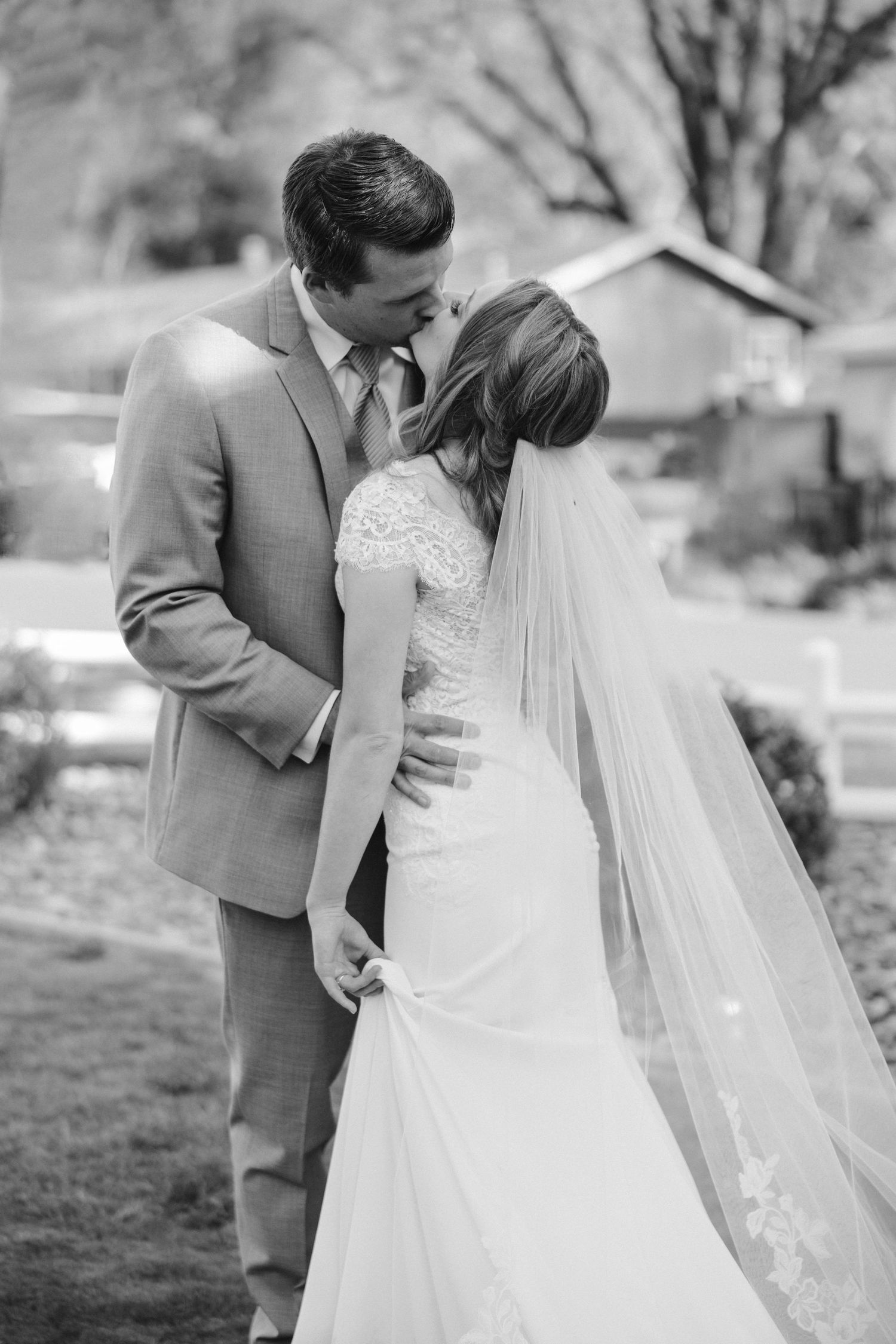 A black and white portrait of newlyweds sharing a tender embrace outdoors.