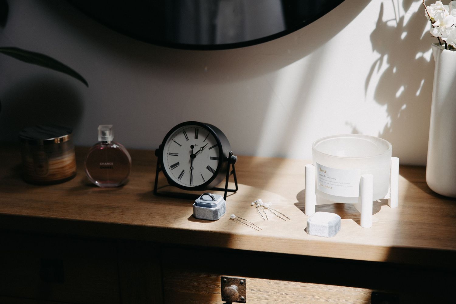 Wooden shelf with clock, perfume bottle and decorative items in soft natural light.