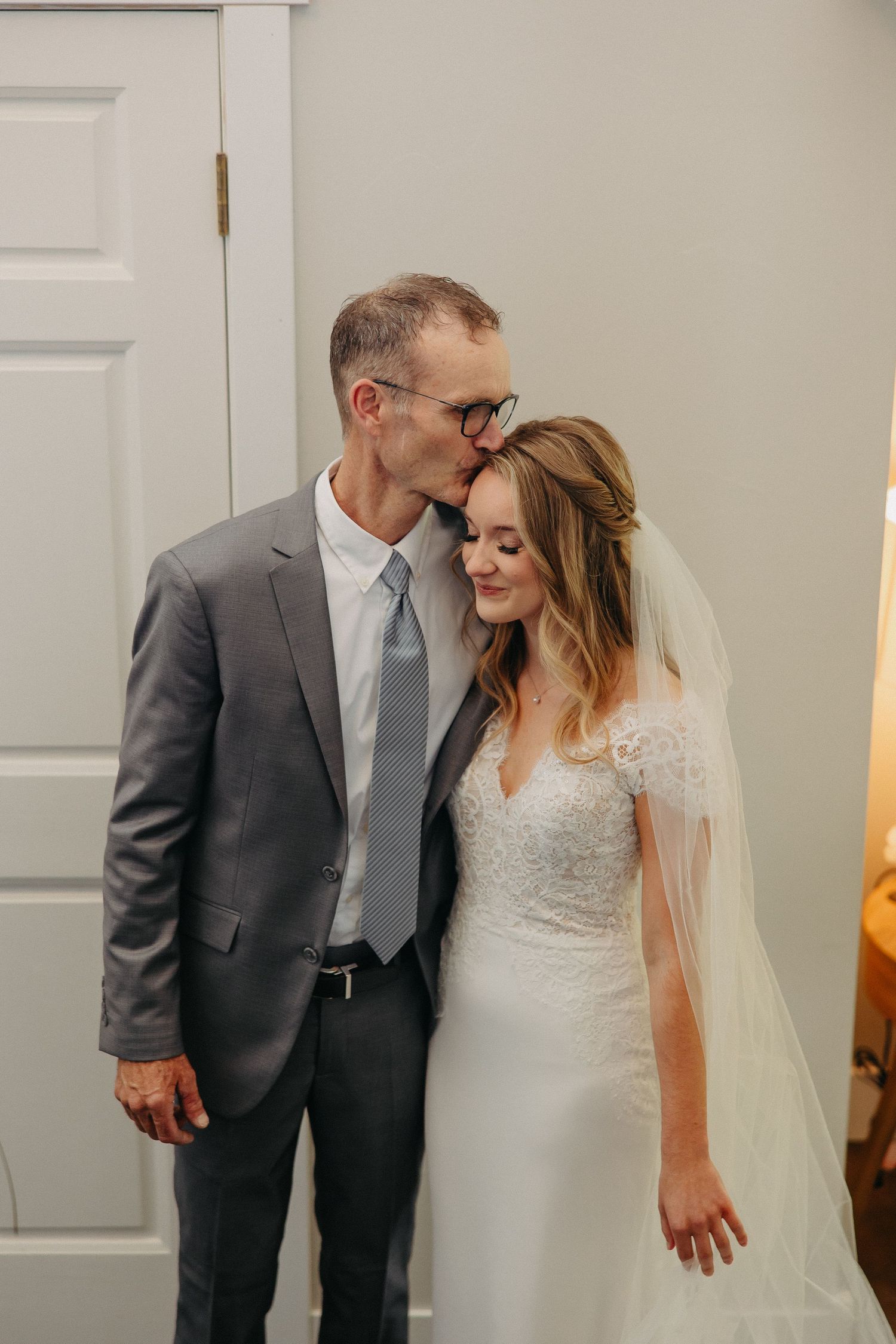 Intimate wedding moment captured indoors with soft lighting and neutral backdrop.