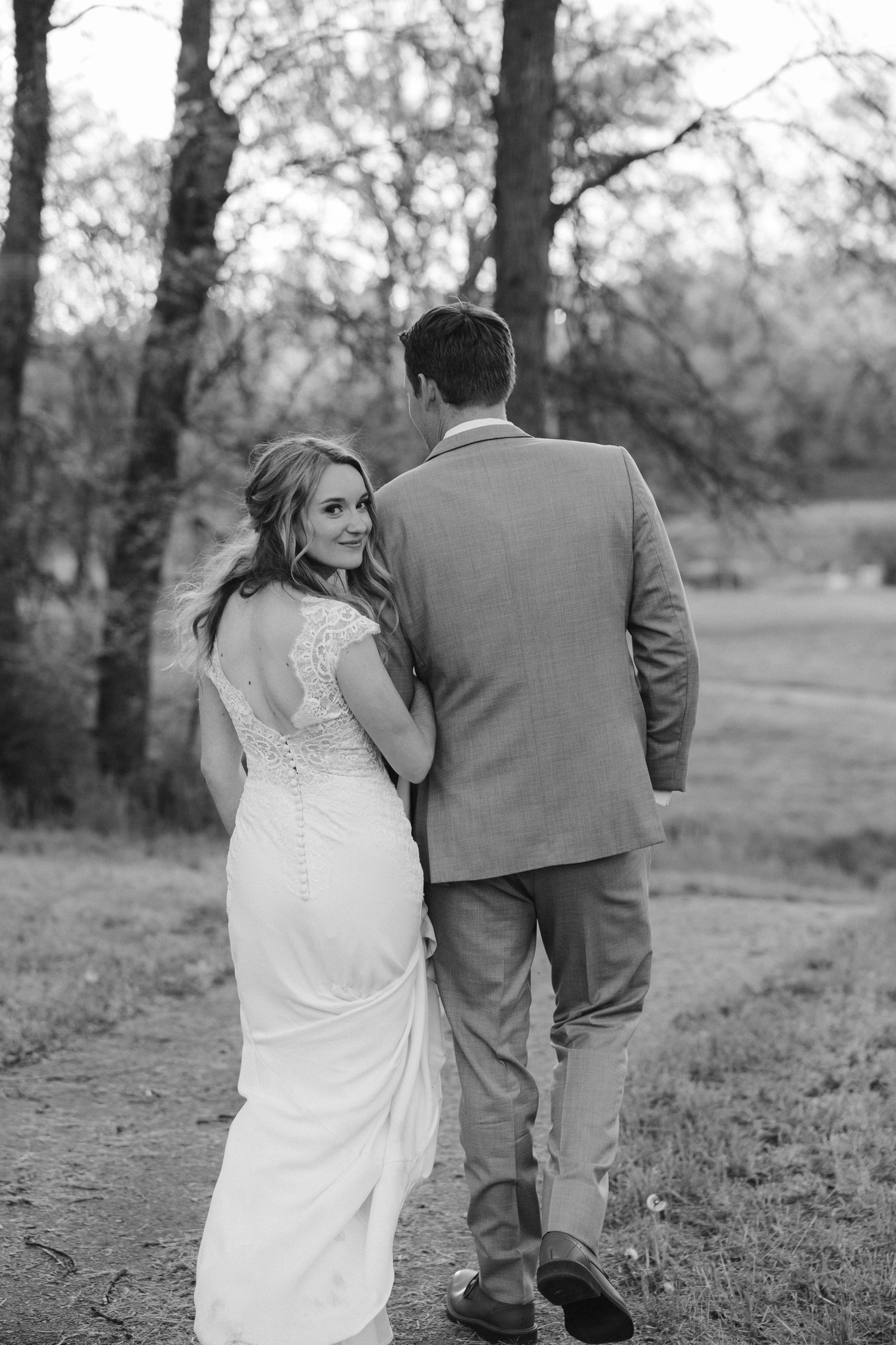 Black and white wedding photo capturing couple's intimate moment on nature trail.