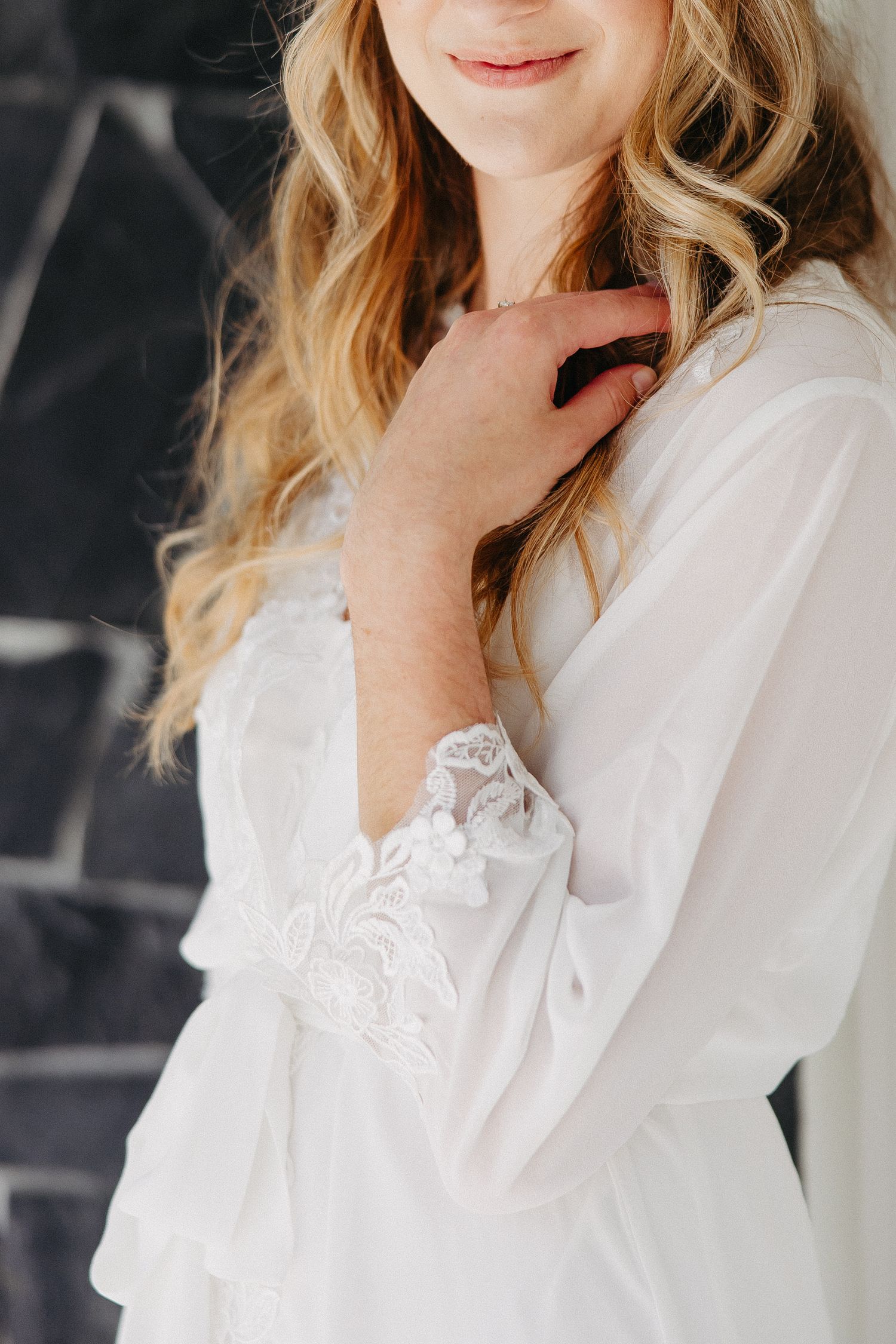 Close up detail of delicate lace sleeve on white bridal robe.