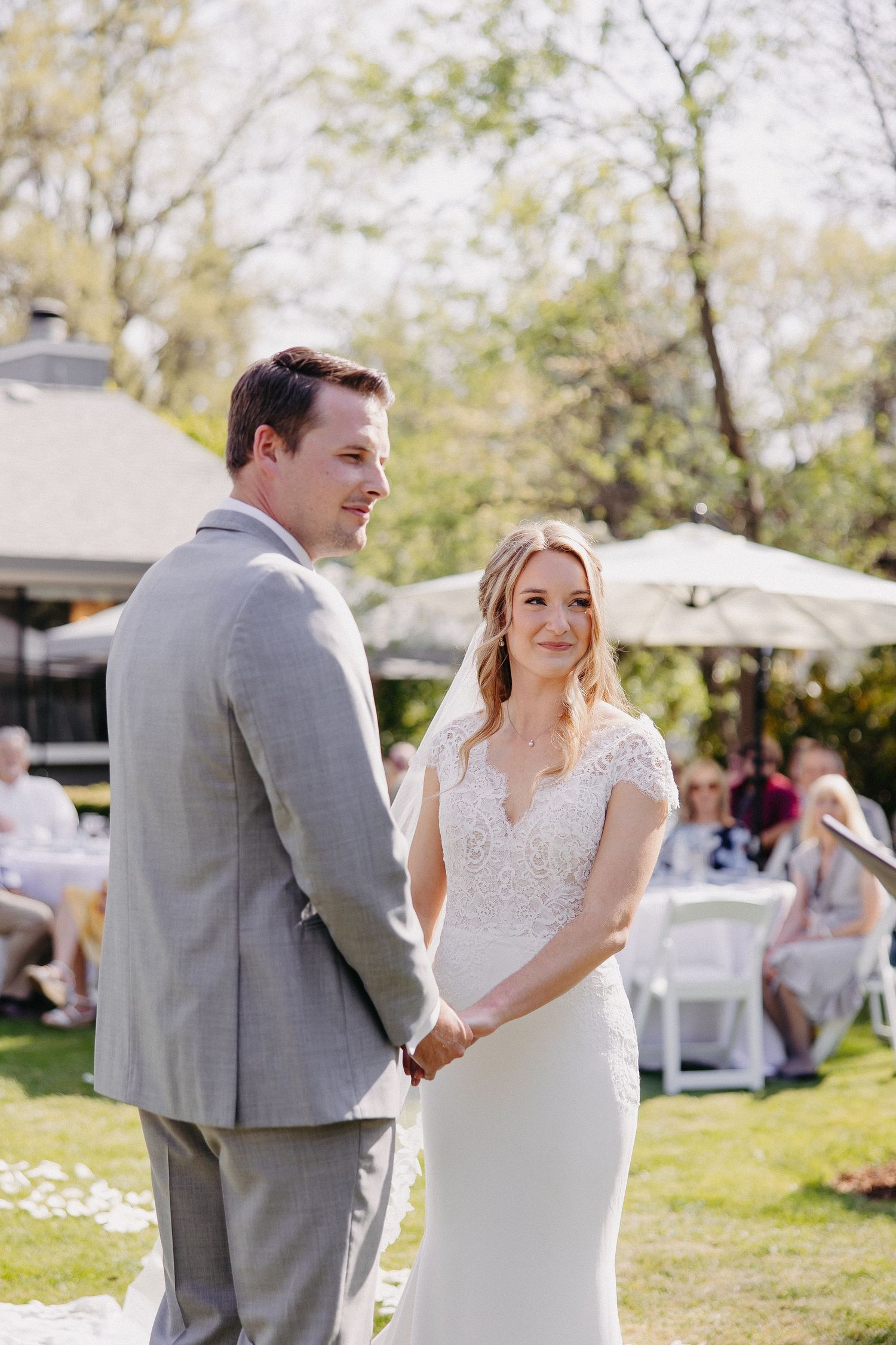 Couple standing together during outdoor spring wedding ceremony with guests seated behind.