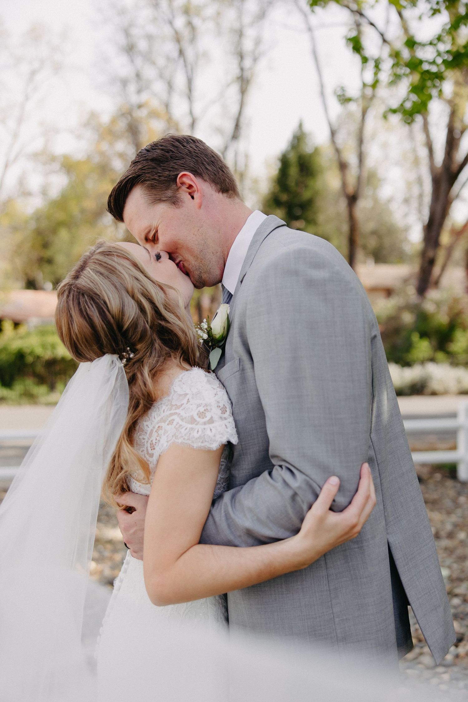 Romantic wedding moment captured as the couple shares a tender embrace in an outdoor garden.