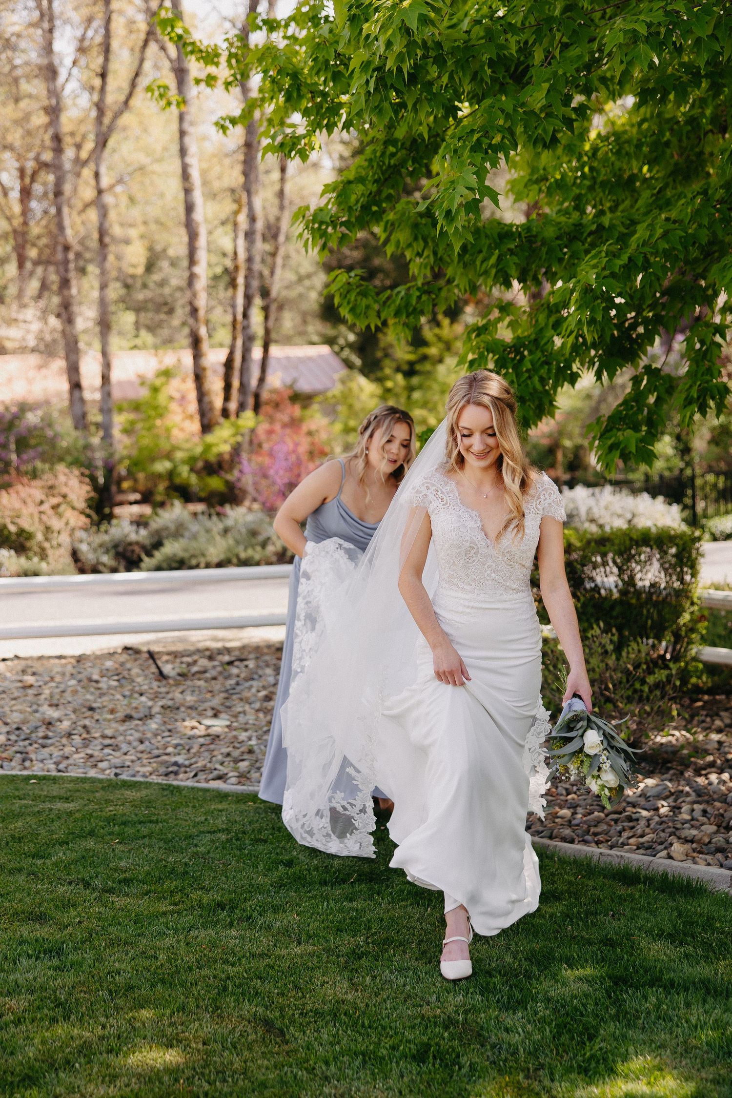 Outdoor wedding scene with flowing white dress and garden landscape.