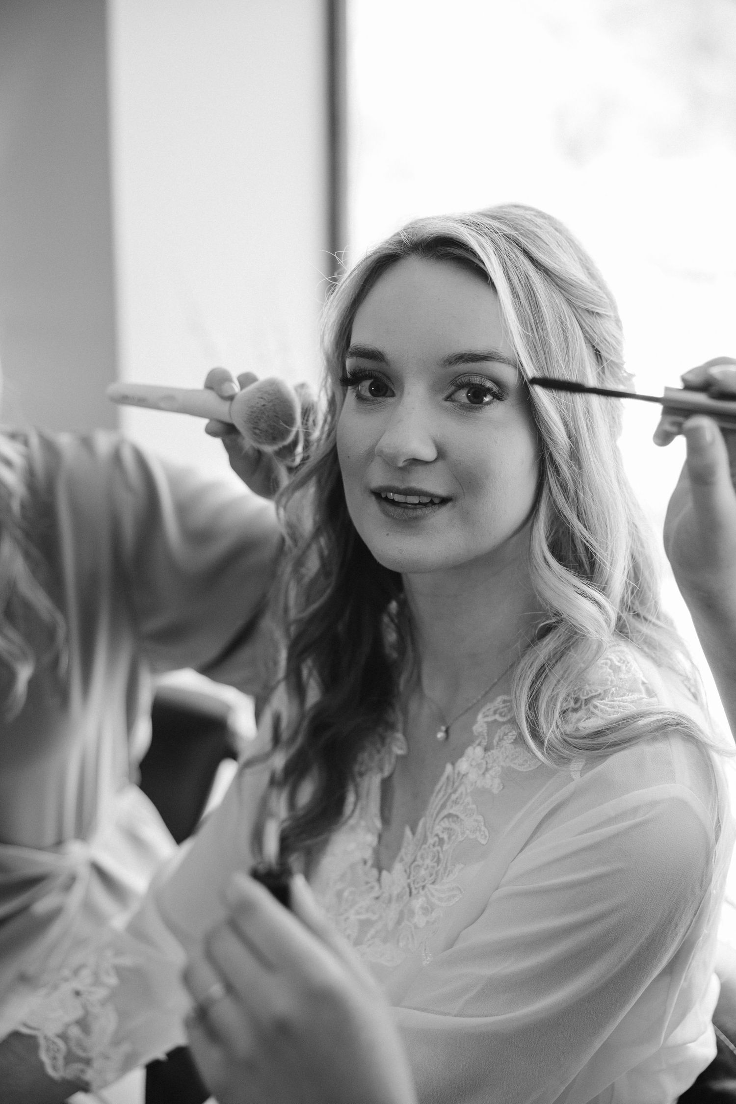 A close-up black and white photo capturing hair and makeup preparation.