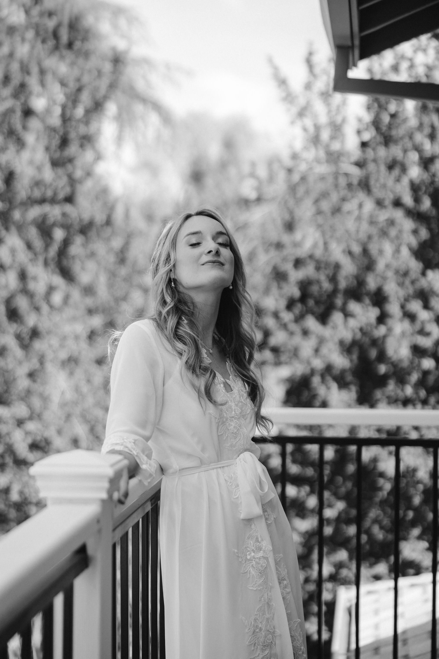 Black and white portrait on balcony wearing flowing white robe.