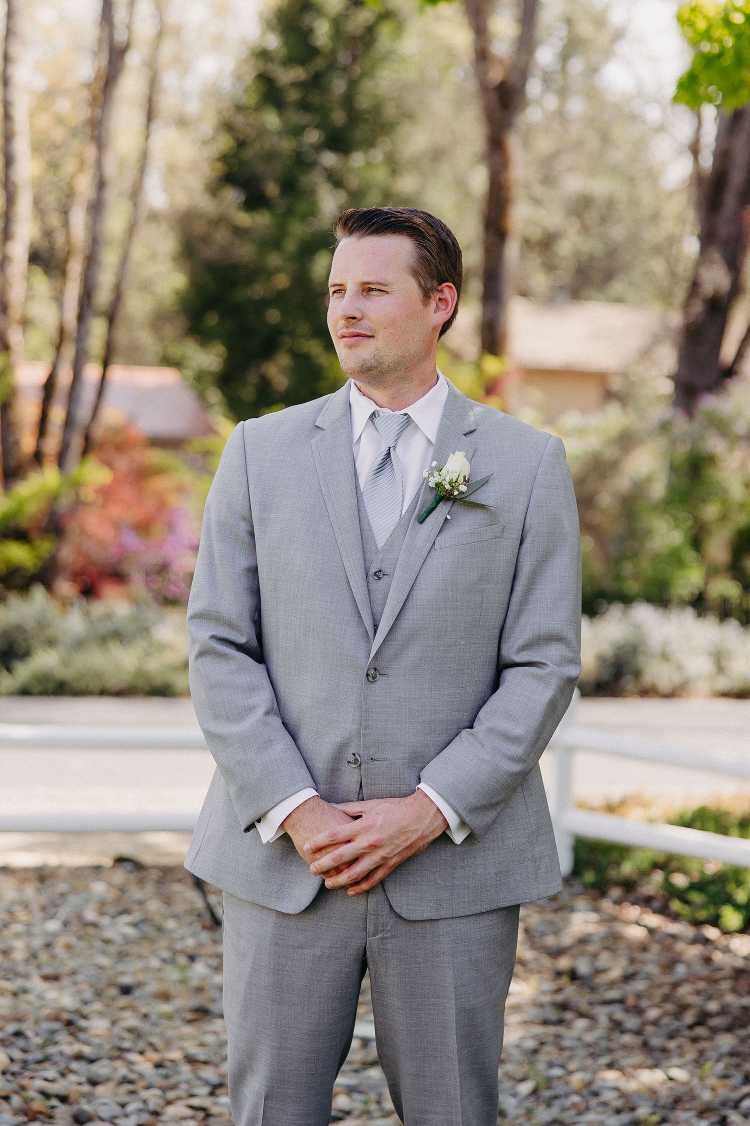 Professional wedding photography showing formal grey suit and tie in an outdoor garden setting.