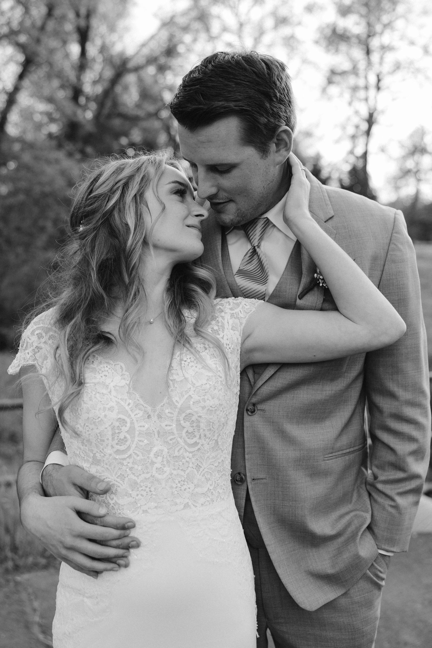 Intimate black and white portrait of newlyweds embracing during outdoor wedding photoshoot.