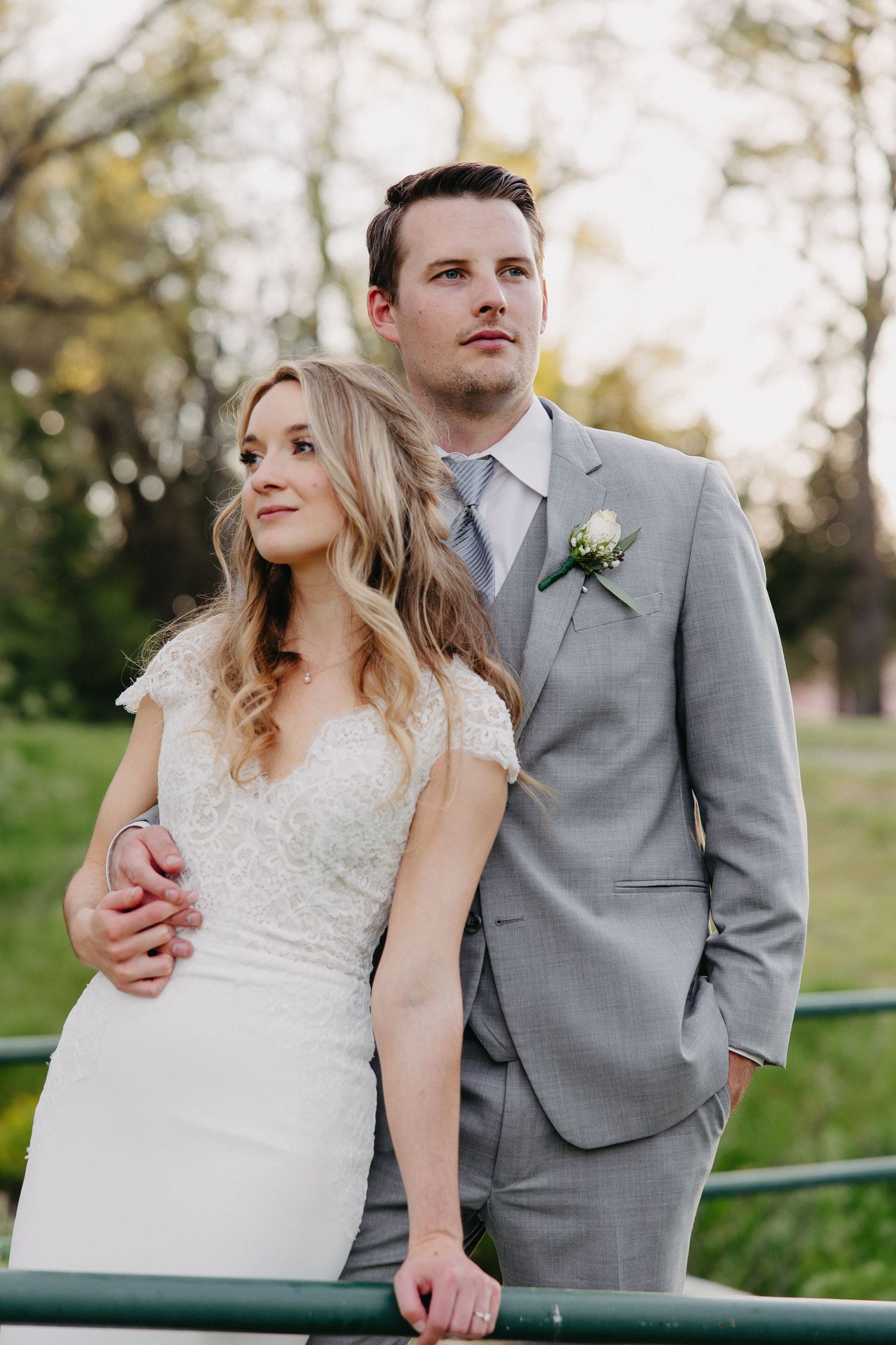 Couple shares romantic moment against garden railing during spring wedding portraits.