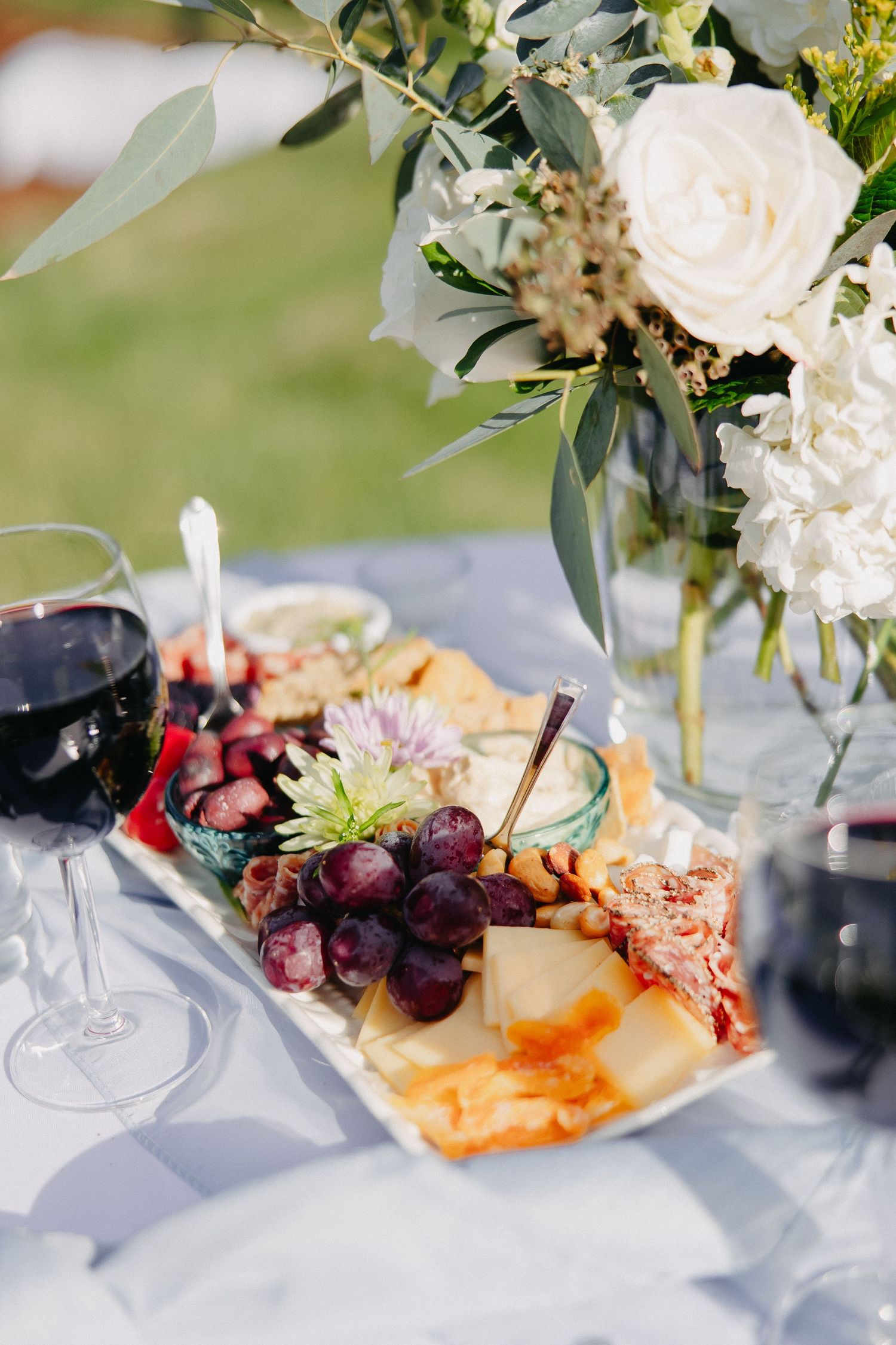 Elegant appetizer plate with grapes, cheese and white roses centerpiece at wedding reception.