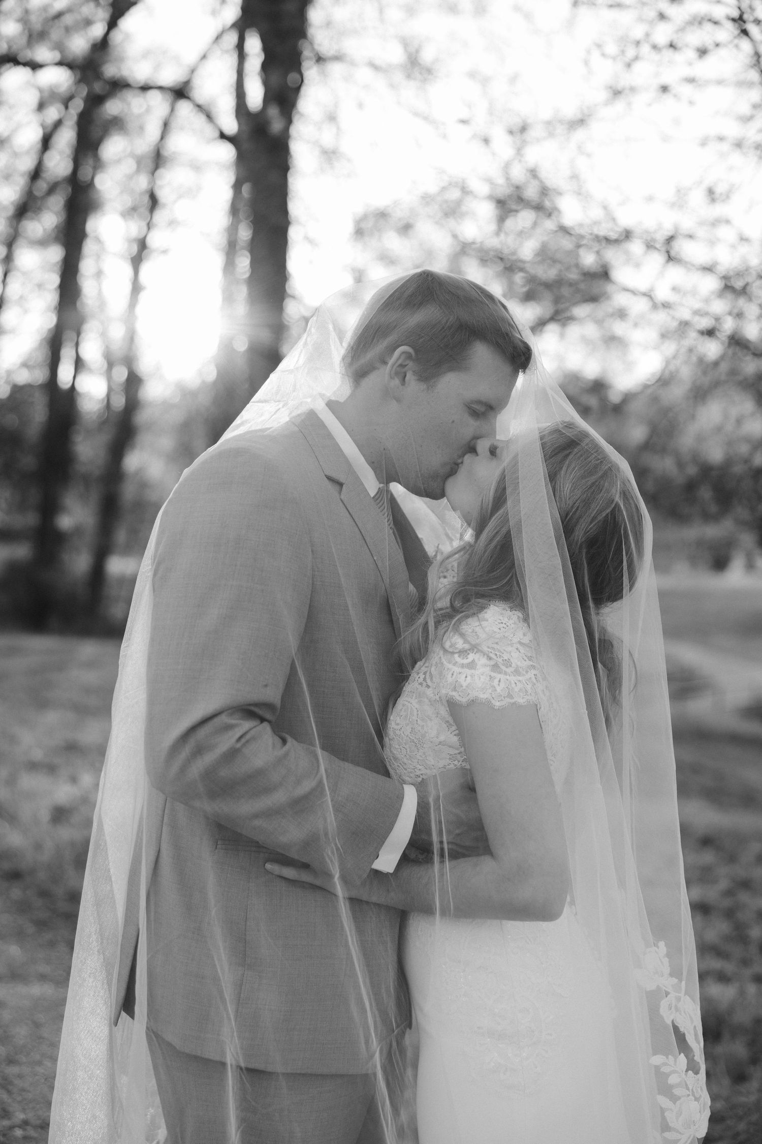 Black and white wedding portrait of a couple sharing an intimate moment outdoors.