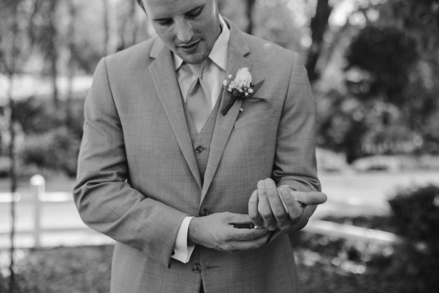 Black and white photograph of formal attire details showing suit buttons and boutonniere.