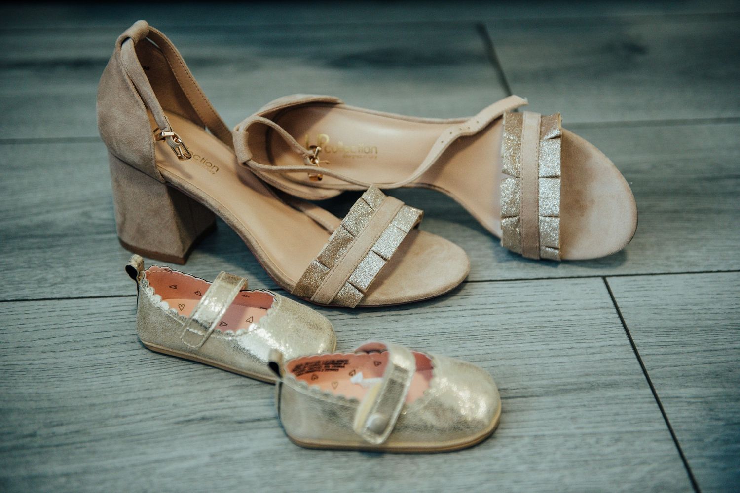 Adult and child formal shoes arranged on a wooden floor, showcasing generational footwear.