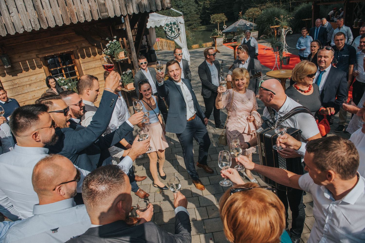 A festive crowd gathered at an outdoor wedding reception sharing drinks and celebrating together.