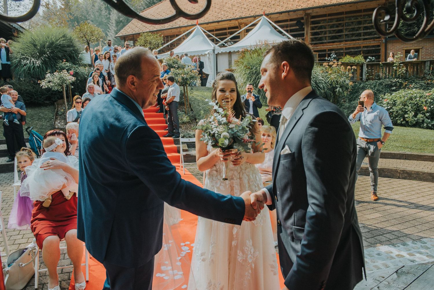 An outdoor wedding ceremony with handshakes and congratulations on a stone patio.