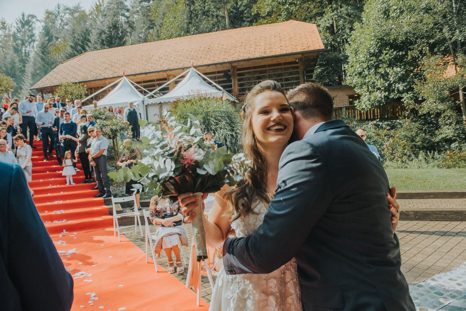 A joyful celebration moment during an outdoor wedding with a red carpet.