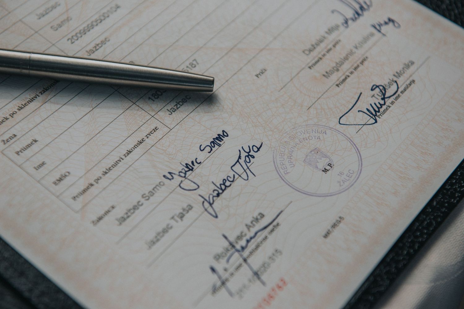 A close-up shot of a pen resting on a signed document with official seals.