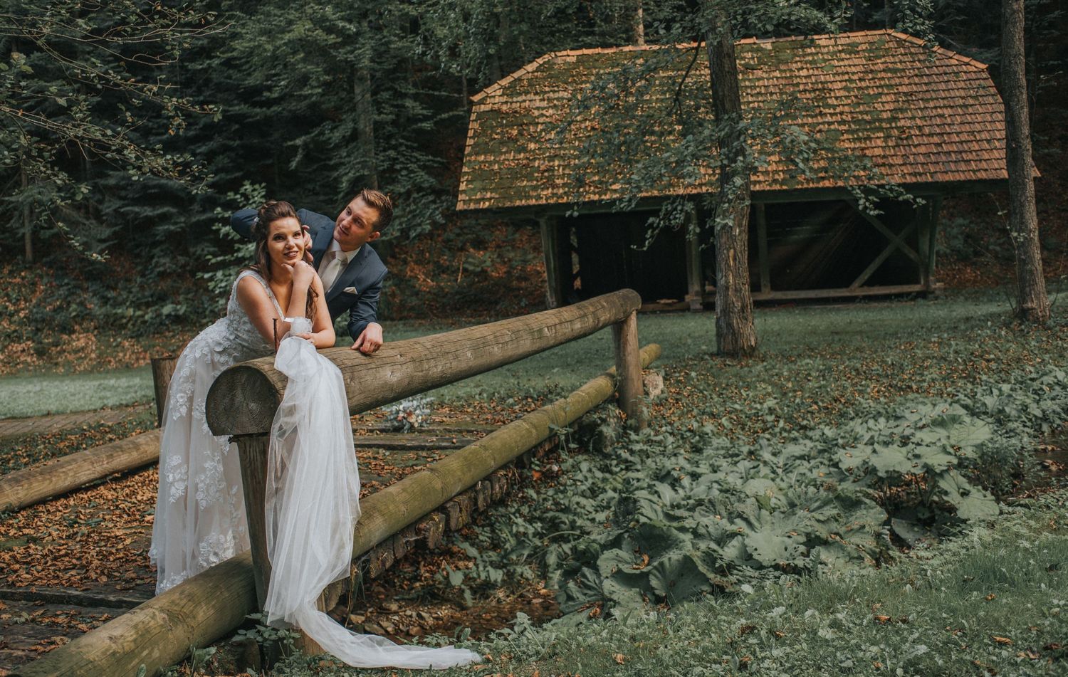 Romantic woodland scene with couple by rustic wooden fence and log cabin in autumn forest setting. Hiša Lisjak