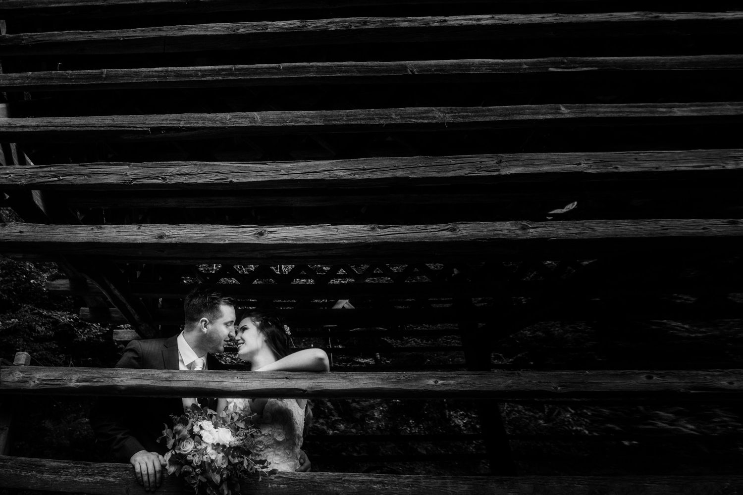 Black and white intimate portrait through wooden steps creating dramatic framing.