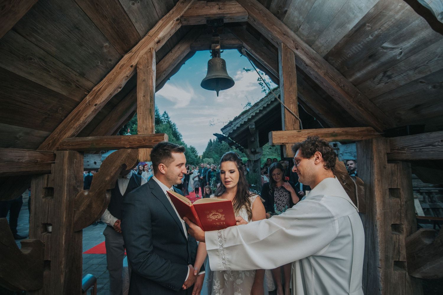 Rustic wooden chapel interior with hanging bell during wedding ceremony.