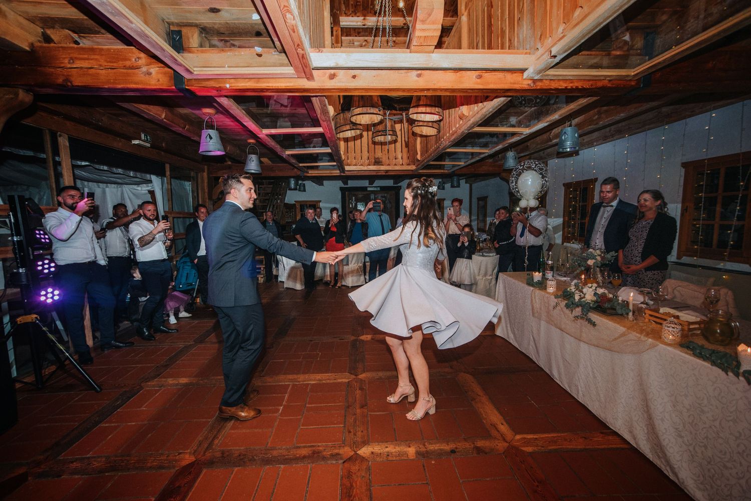 Wedding reception dancing on terracotta floor in rustic indoor venue.