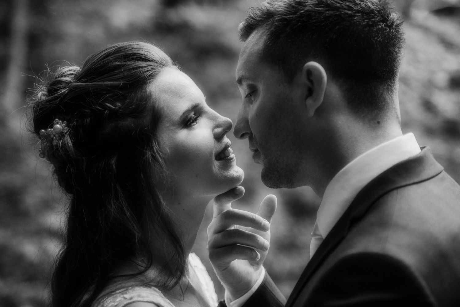 An intimate black and white portrait of a bride and groom sharing a tender moment.
