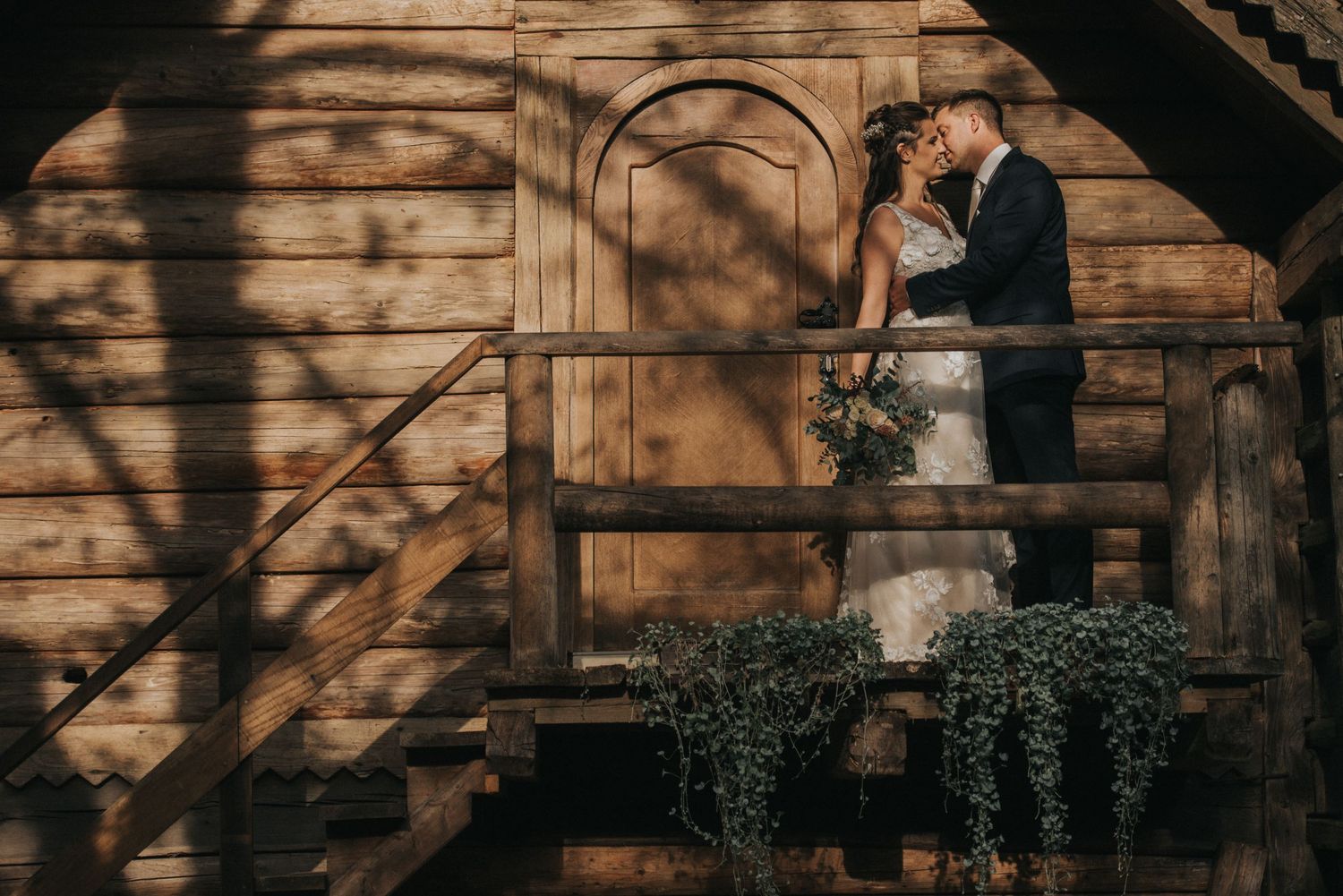 A rustic wedding scene with couple on wooden stairs casting dramatic shadows.