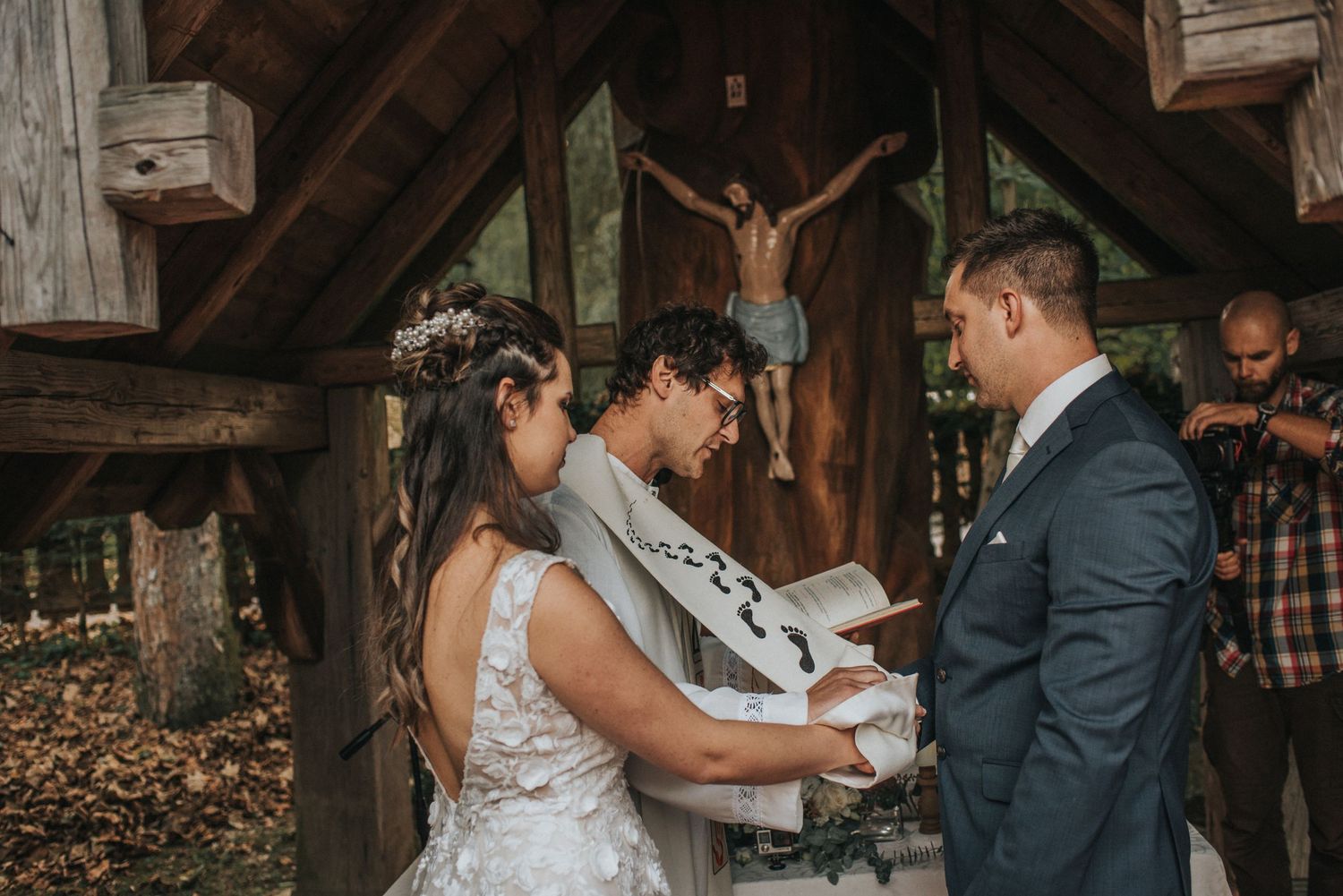 Wedding ceremony in rustic wooden chapel with exposed beams and natural lighting.