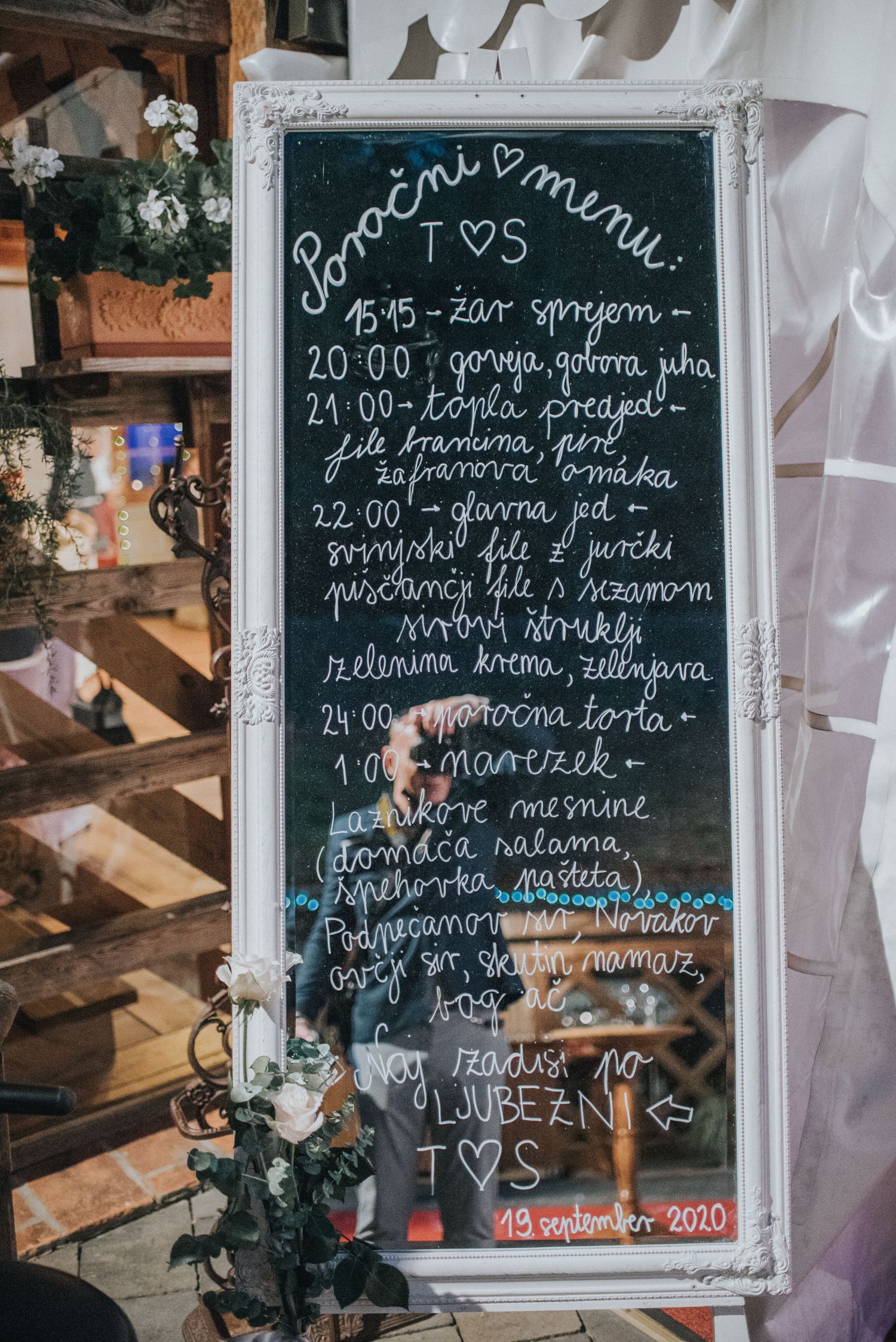 Wedding reception menu written in white on ornate framed chalkboard with decorative details.