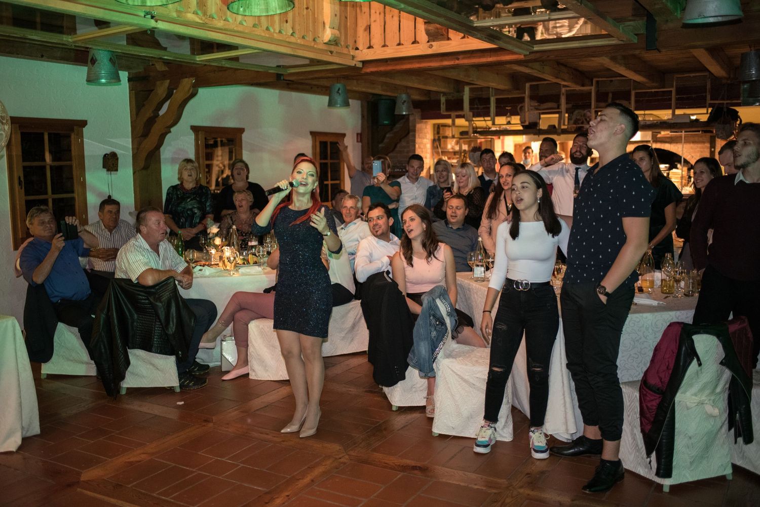 Wedding guests dancing and celebrating on wooden dance floor at indoor reception.