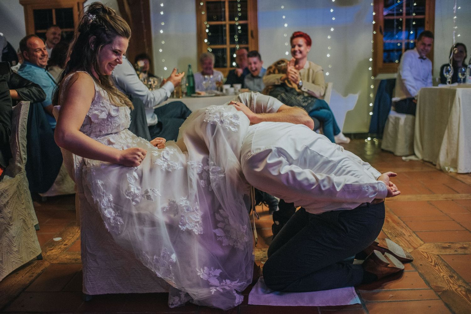 Wedding party celebration with playful garter removal tradition.