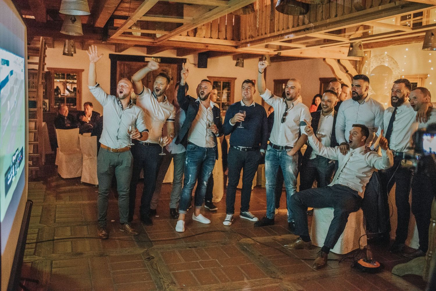 Group of men in matching outfits dancing and celebrating at wedding reception.