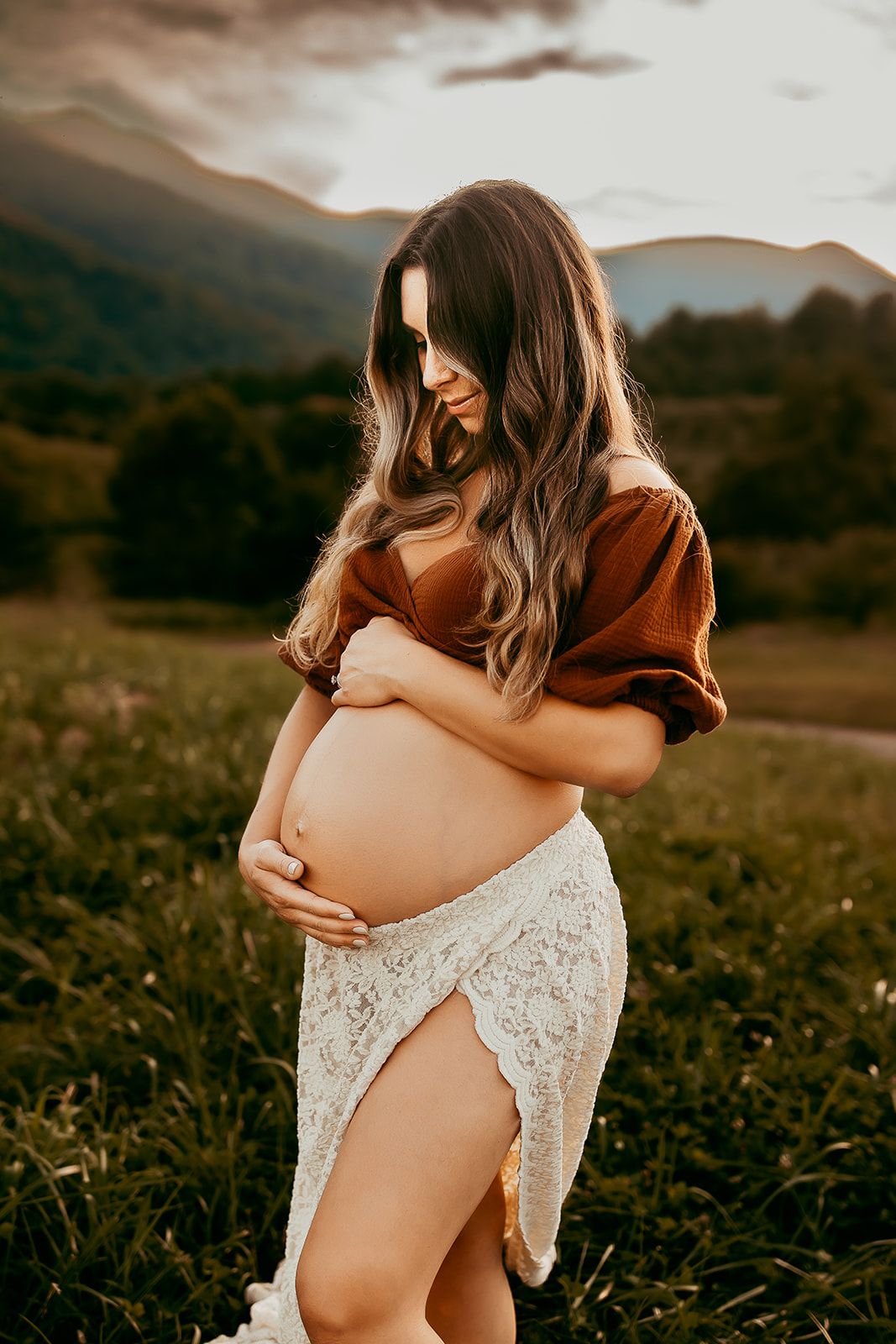 A pregnant mother looks down at her baby bump during her maternity session.