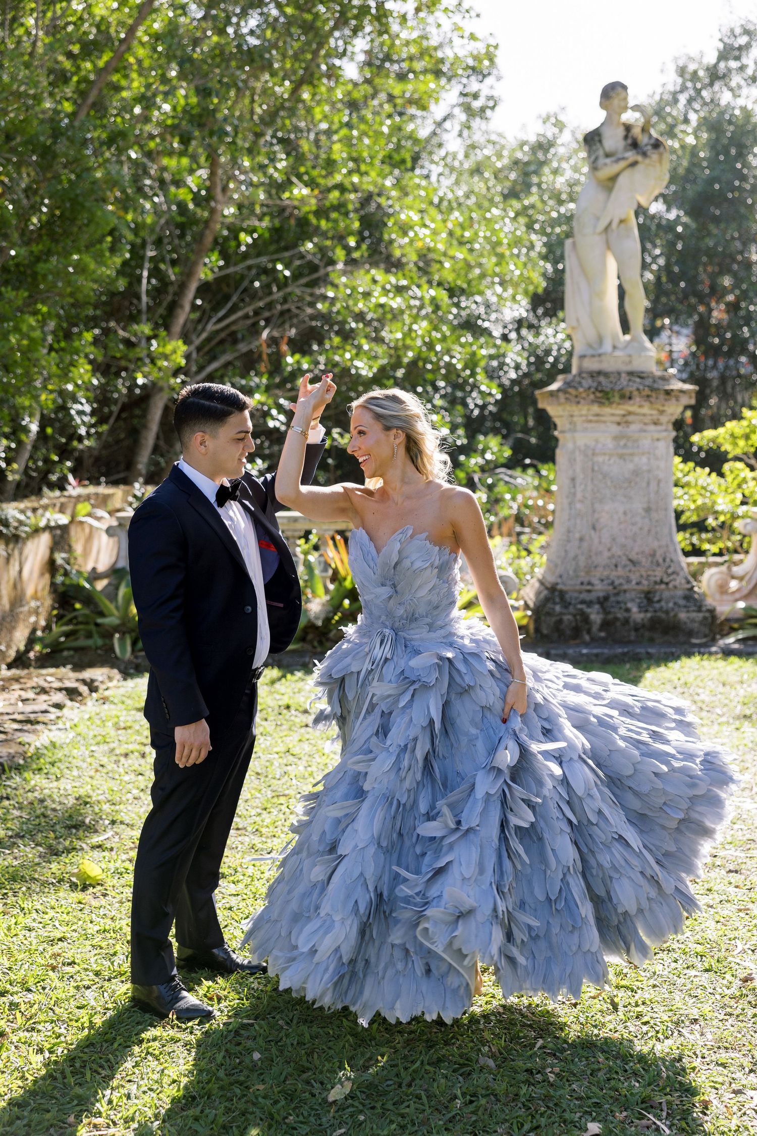 A stunning light blue ruffled ball gown at an elegant garden photoshoot with classical statuary in the background.