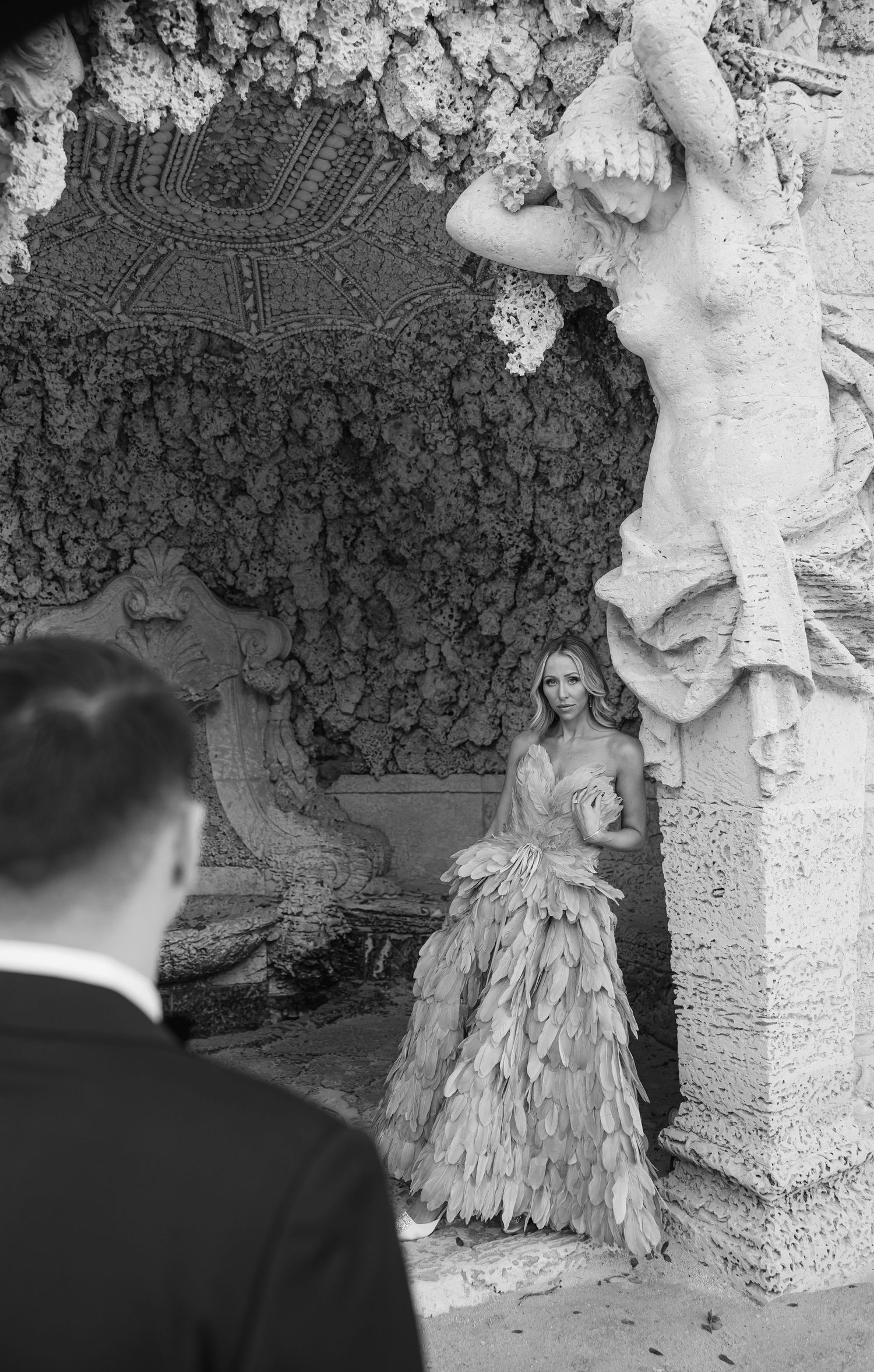 A black and white photo in a grotto setting with classical statuary and ornate stonework.