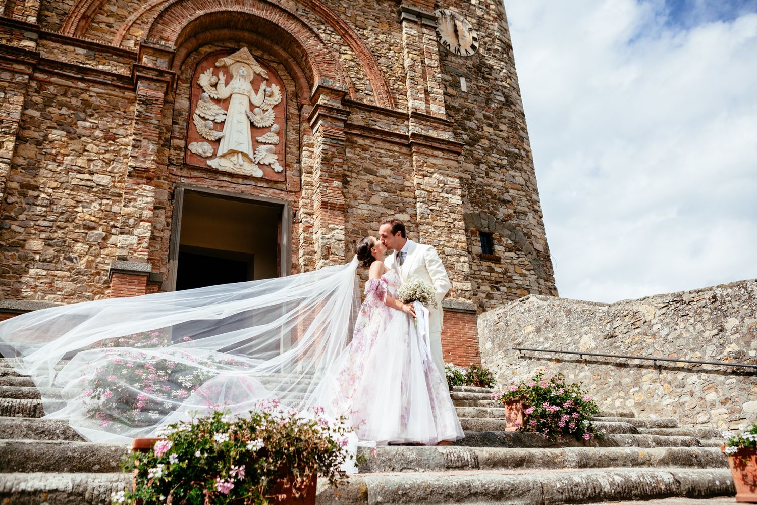 bride and groom stand on the steps of a Tuscan church and kiss
