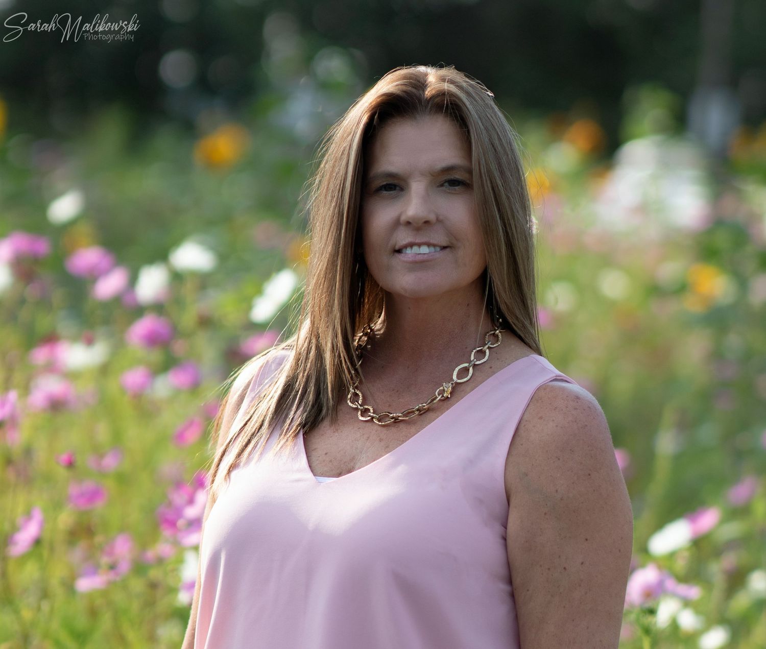 A summer portrait in a vibrant wildflower field with pink cosmos blooms.