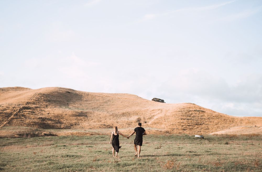 Panoramic view of rolling hills with family silhouettes walking in distance.