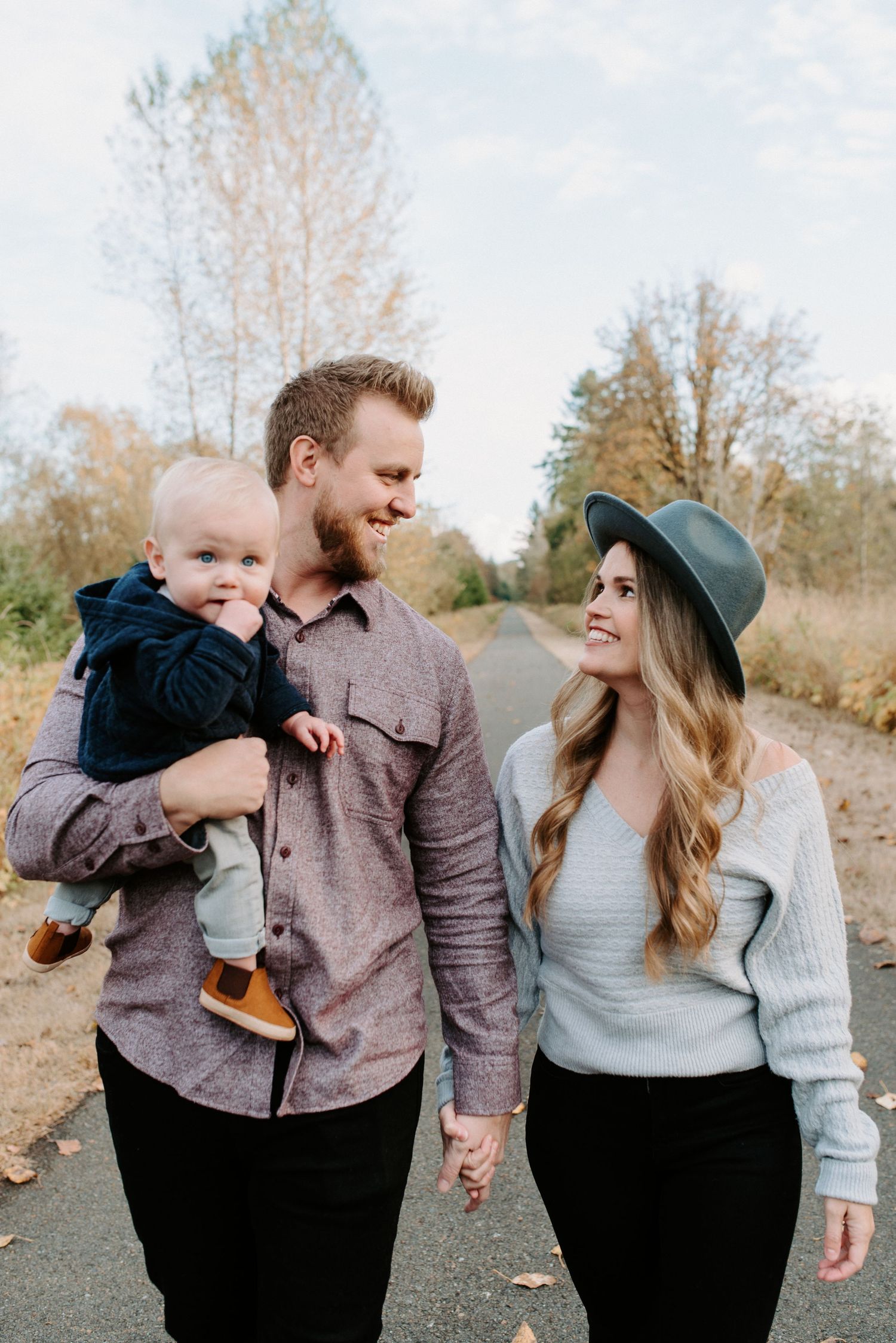 Family sharing playful moments together on outdoor path during autumn.