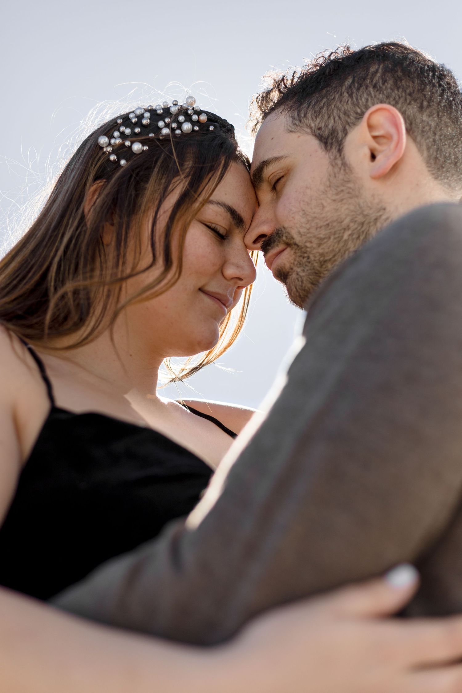A romantic couple share an intimate moment outdoors with soft lighting and delicate hair accessories.