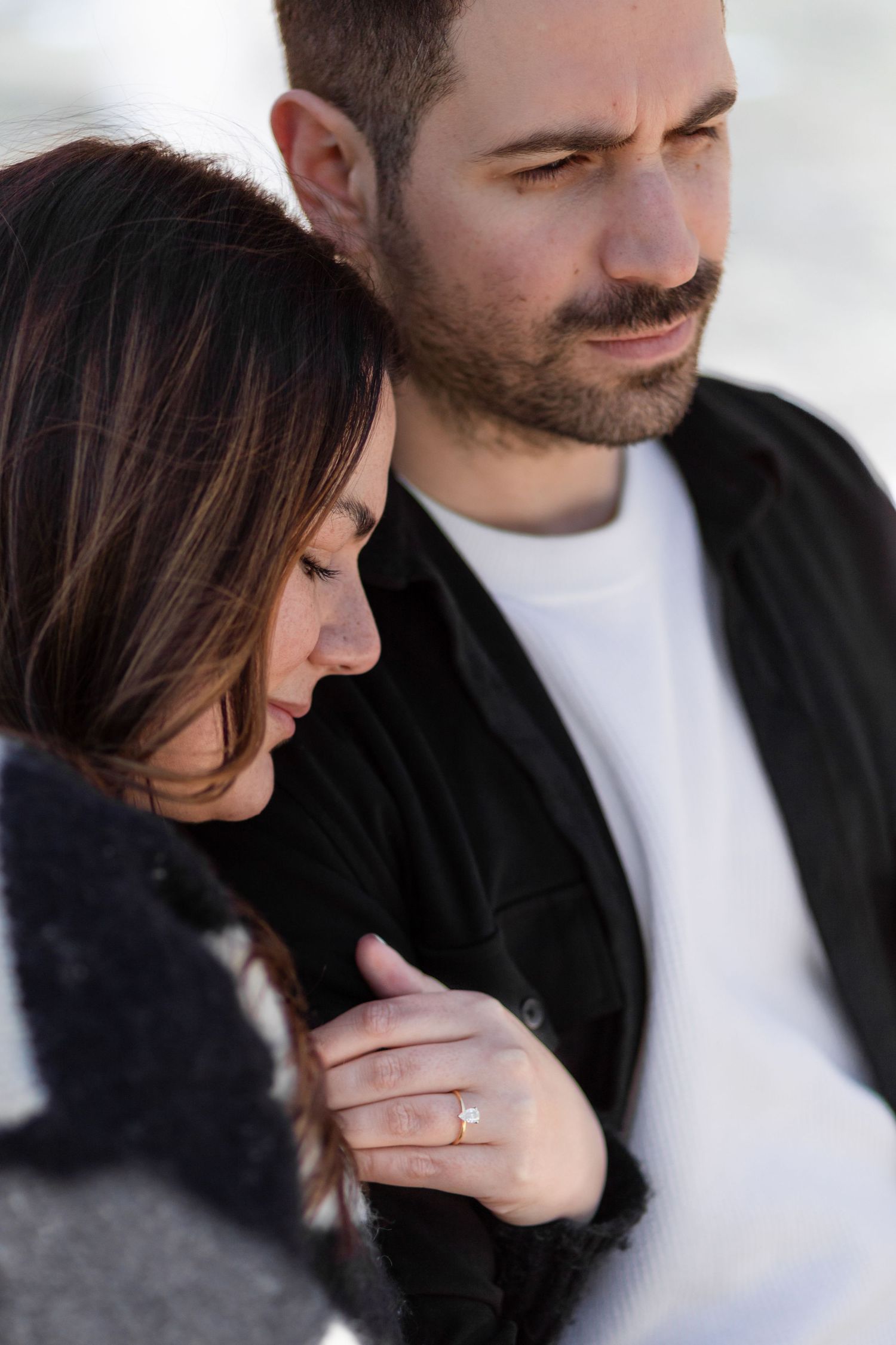 Intimate close-up portrait of a couple in casual winter wear against bright background.