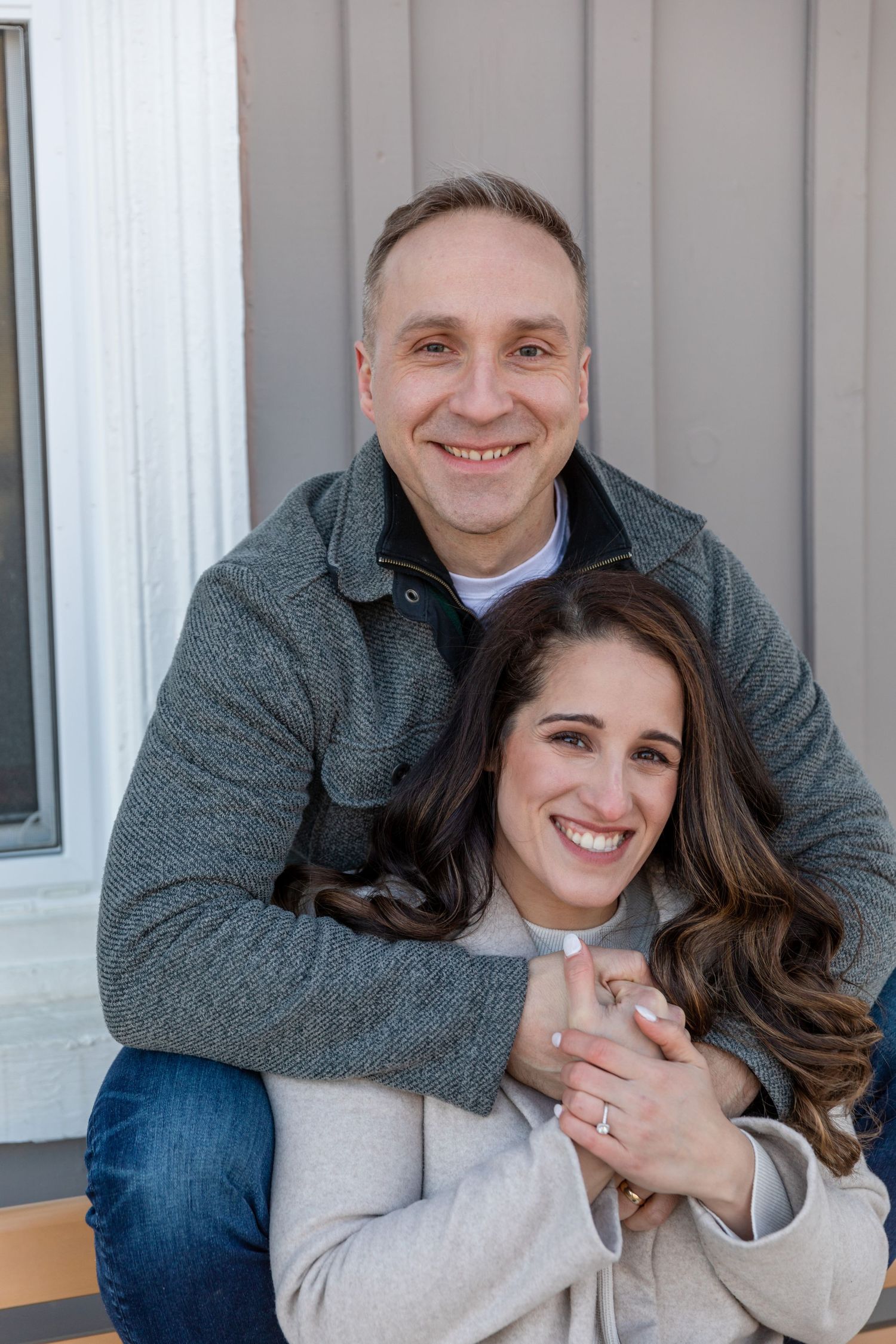 Loving couple poses together outdoors in casual winter clothing.