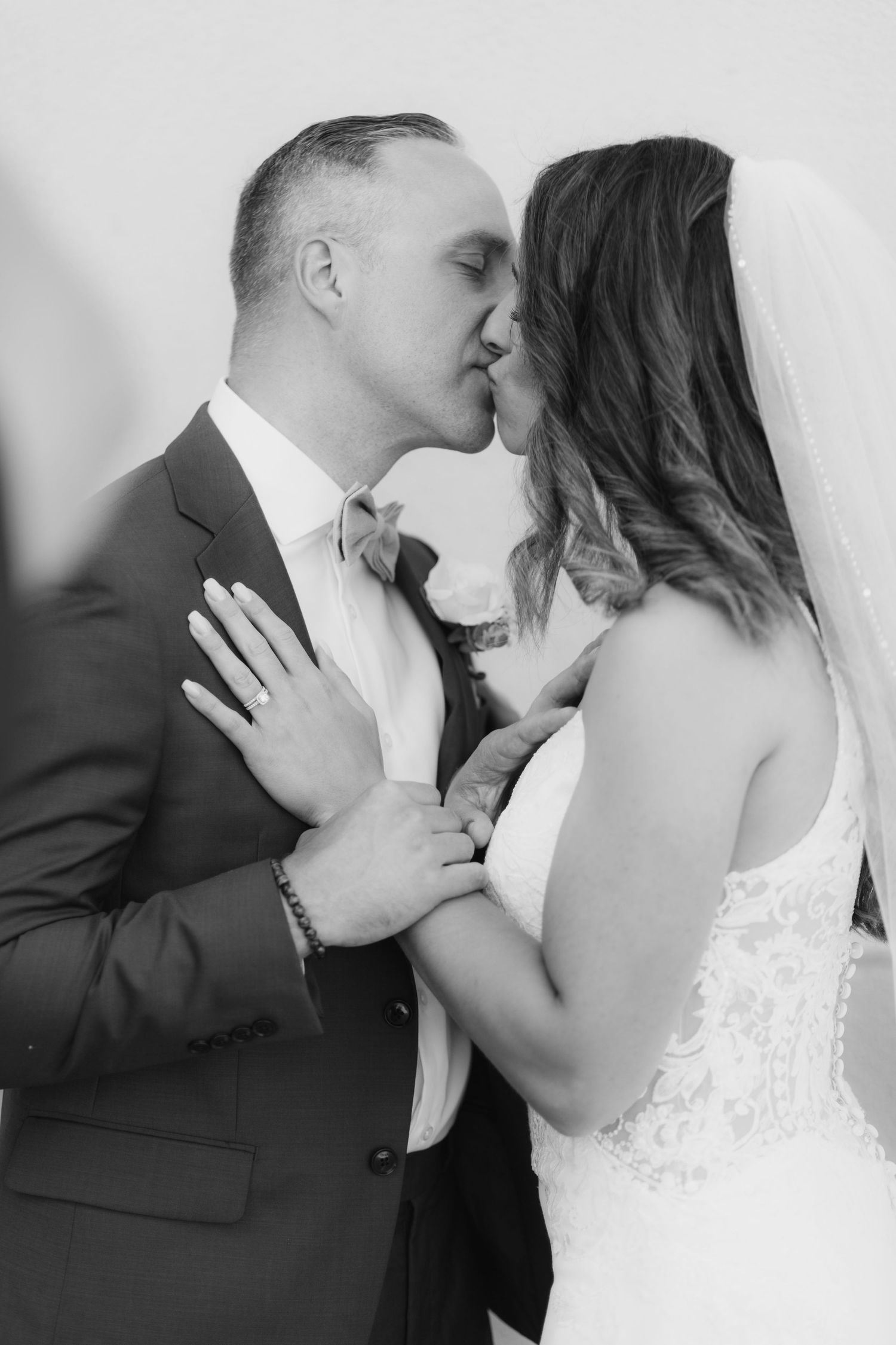 Romantic black and white portrait of newlyweds sharing an intimate kiss.