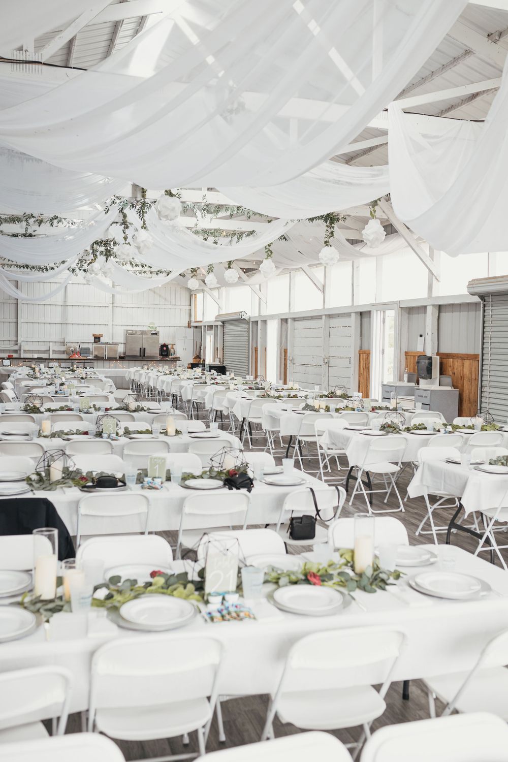 Wedding reception venue with white draped ceiling and tables set for a celebration.